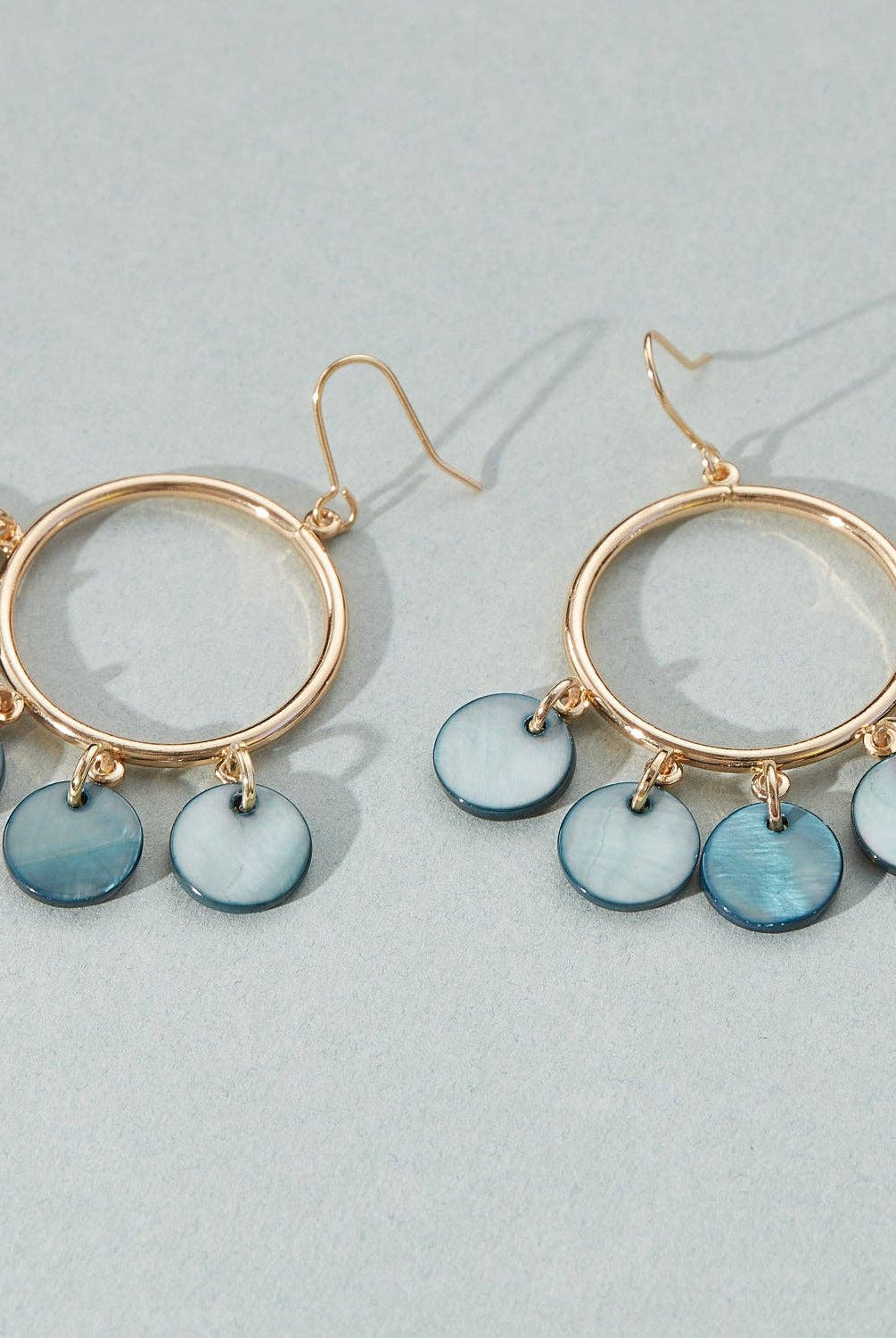Gold hoop earrings with blue disc charms on a light gray background, shell pattern, gold earring, deep blue detail, dangle and hoop, gift, accessory