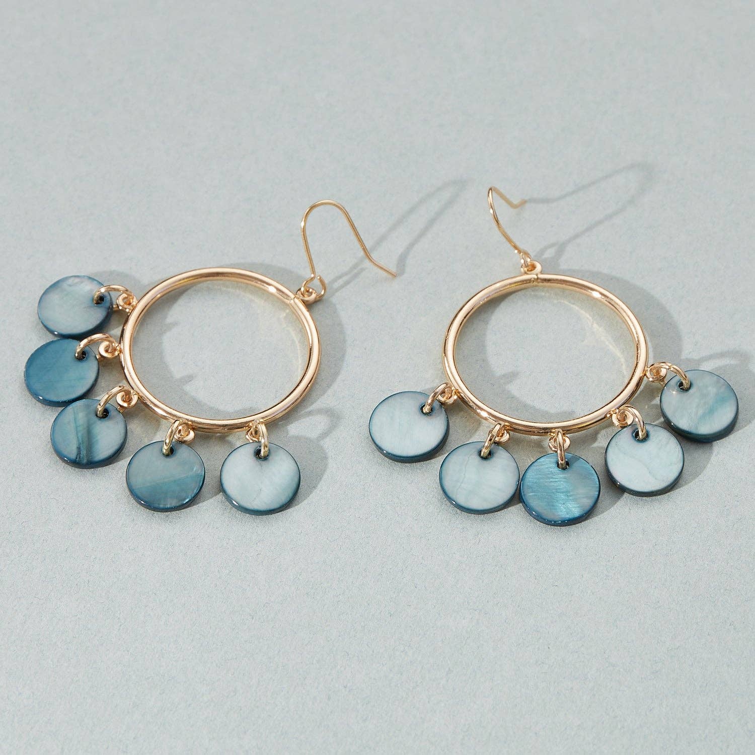 Gold hoop earrings with blue disc charms on a light gray background, shell pattern, gold earring, deep blue detail, dangle and hoop, gift, accessory