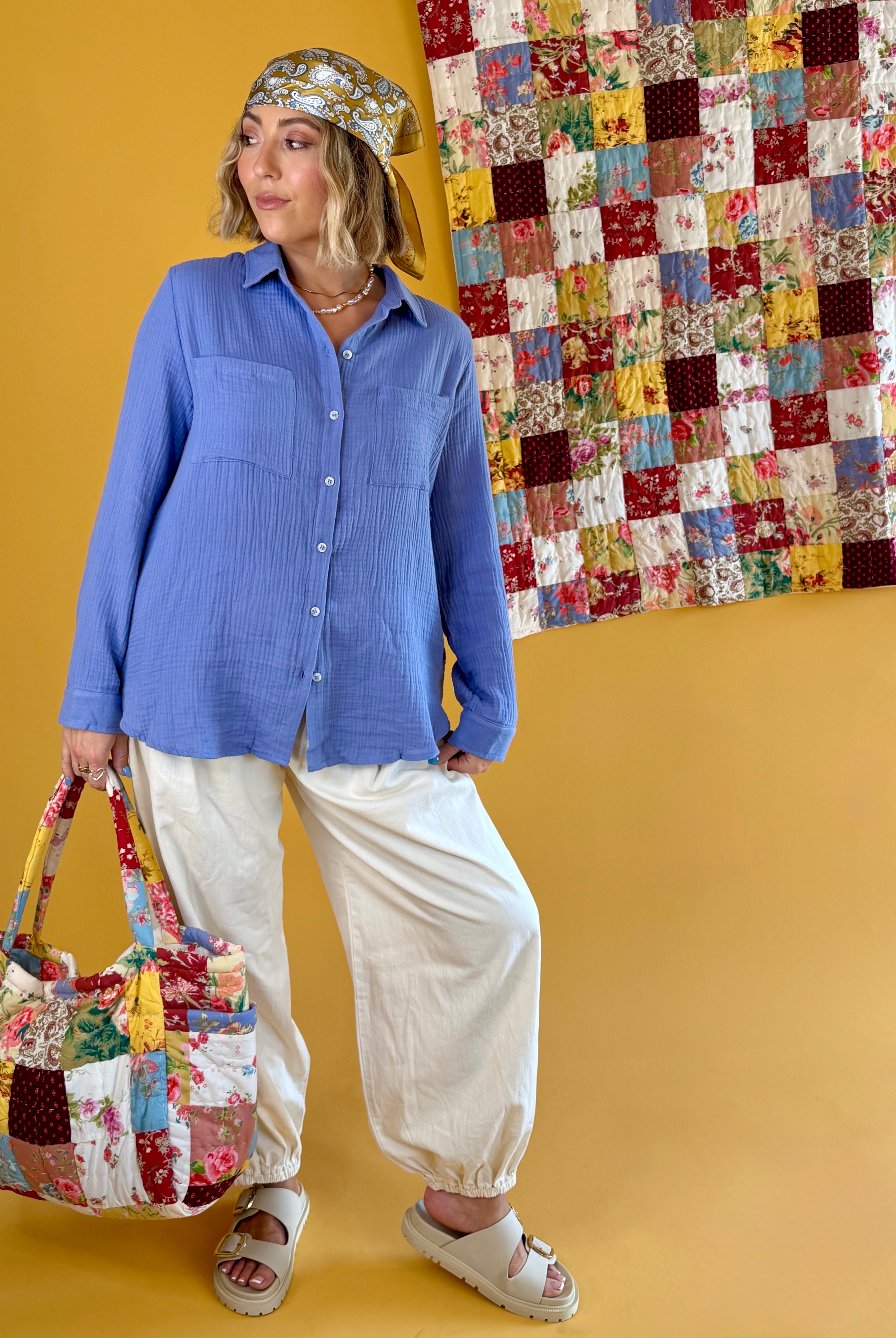 Woman holding a patchwork handbag with a colorful quilt in the background