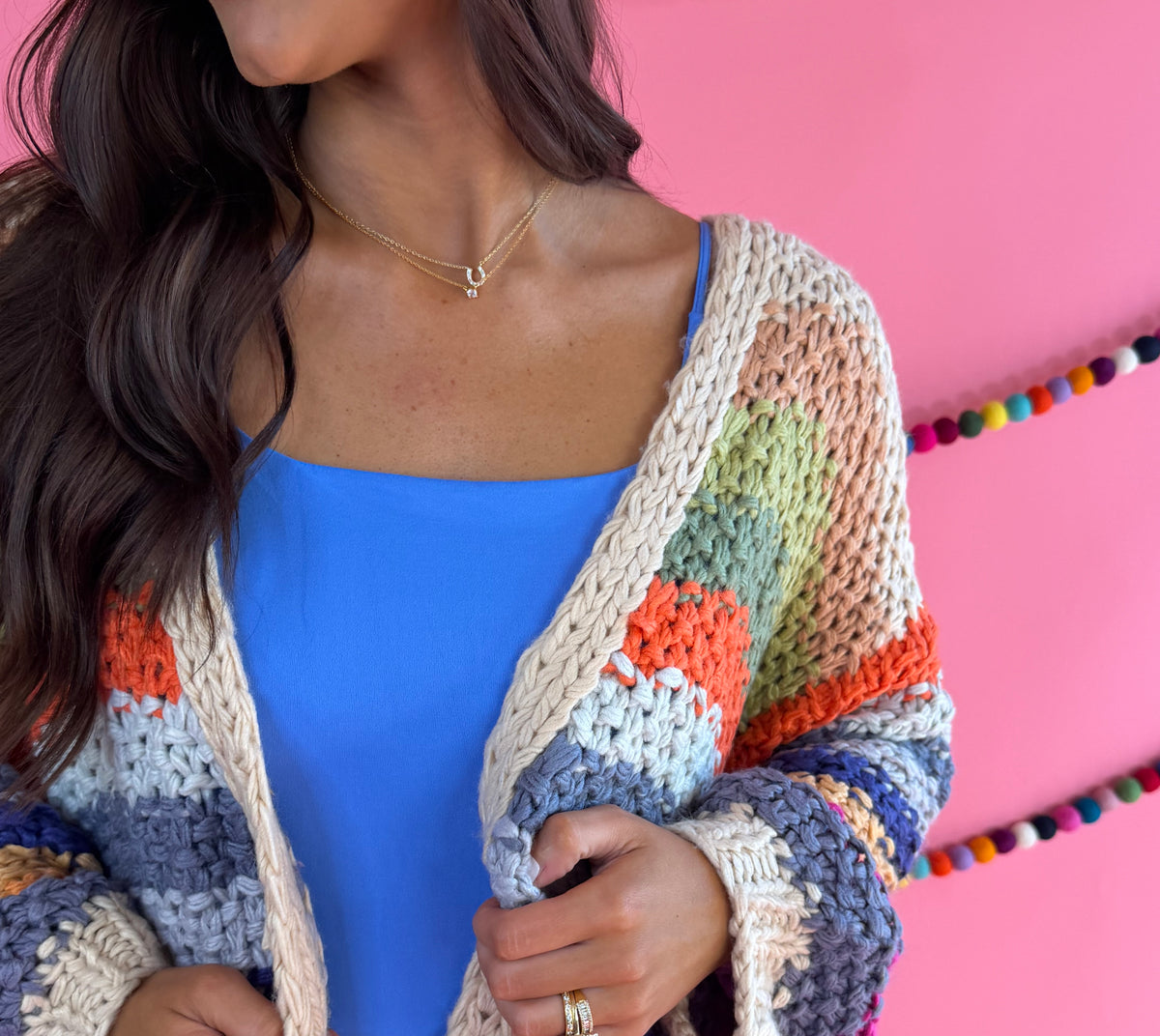 Knit and stripe detail: Cream Rainbow Cardigan with multicolor stripes, an open front, and hip pockets.