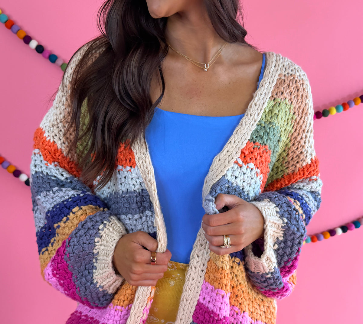 Front fit view: Cream Rainbow Cardigan with multicolor stripes, an open front, and hip pockets.