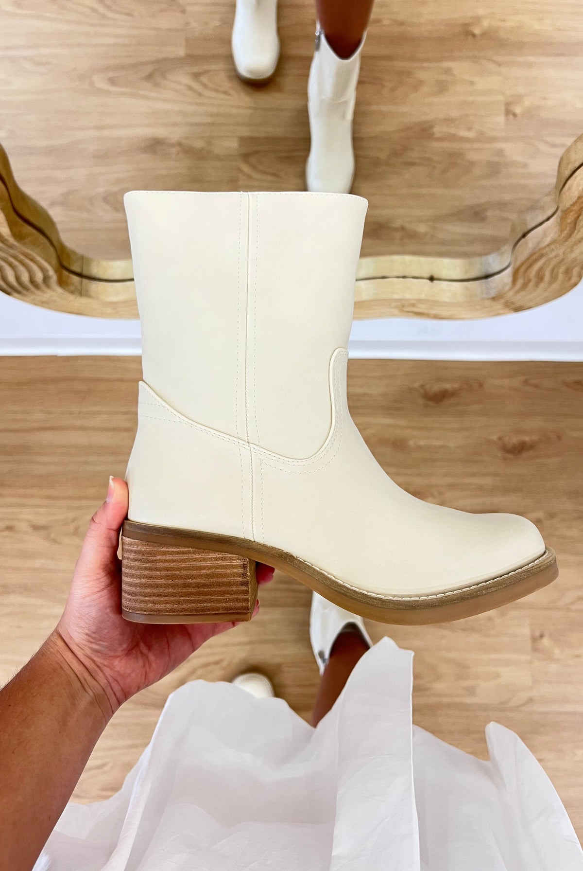 White boot held in a hand with a wooden floor background, TRENDY BOOT, it girl boot, bootie, boho style, coastal, bone