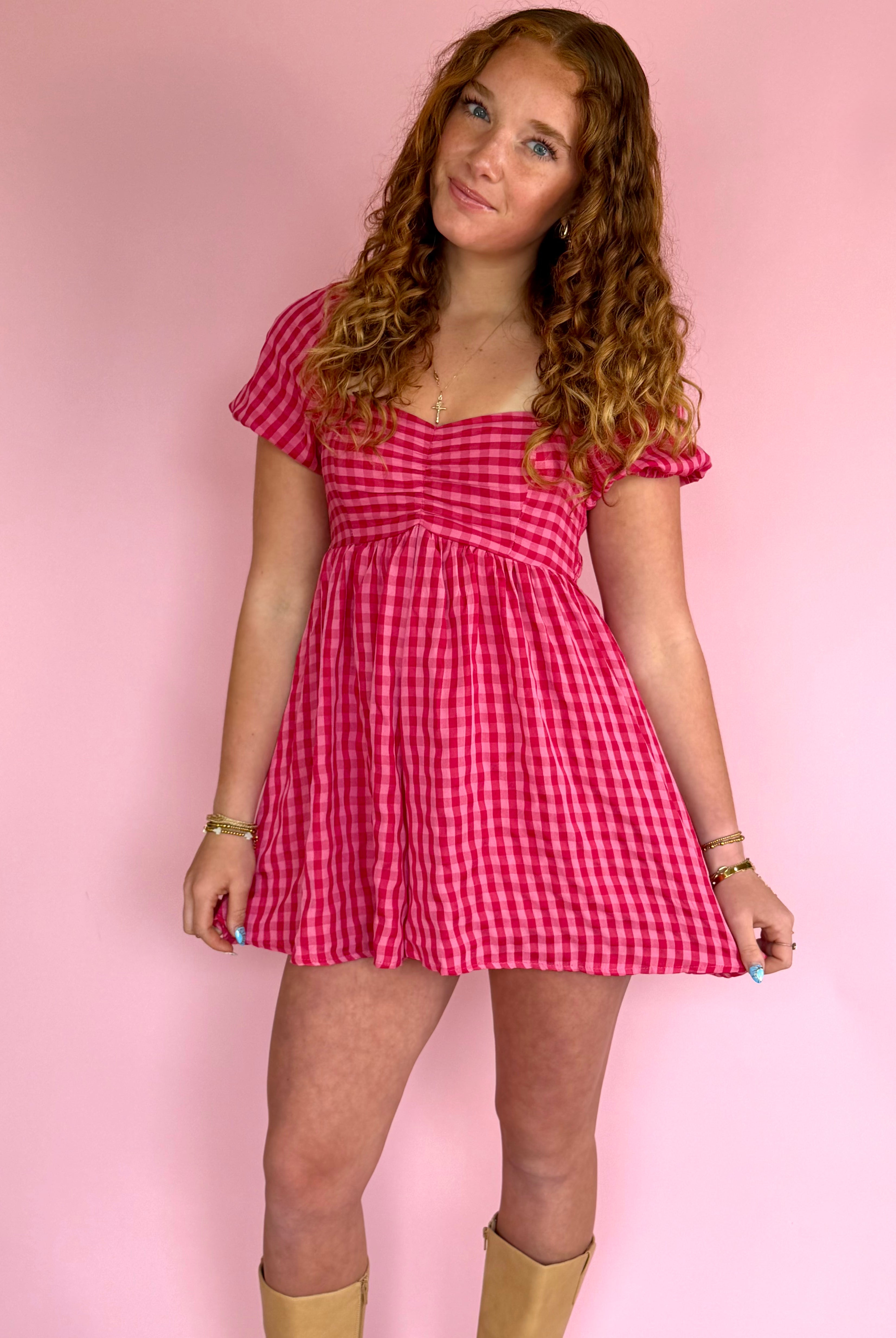 Young woman wearing a red checkered dress against a pink background, red and pink, strawberry field mini dress, flowy and airy, a pink favorite