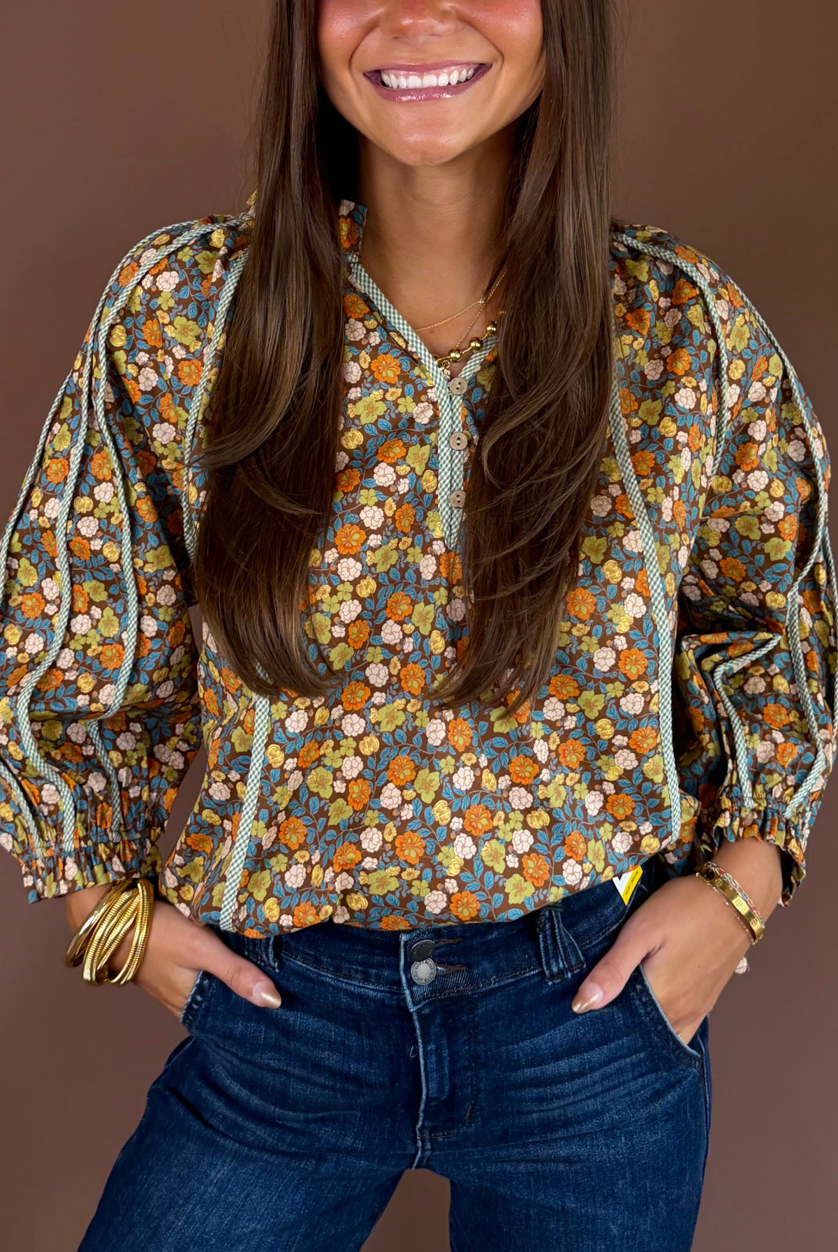 Brown cotton blouse with an allover floral print, V-neckline, three-quarter sleeves, and relaxed fit.
