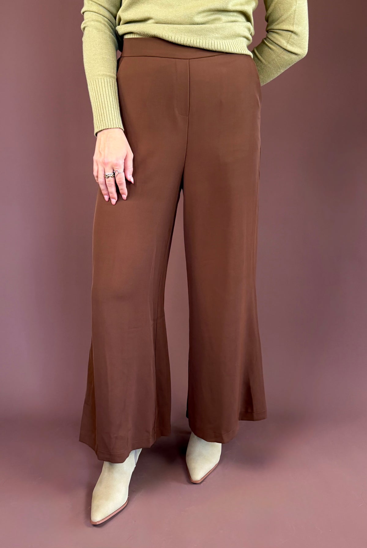 Chocolate brown high-waisted trouser pants with a wide leg, clasp-front closure, and side pockets.