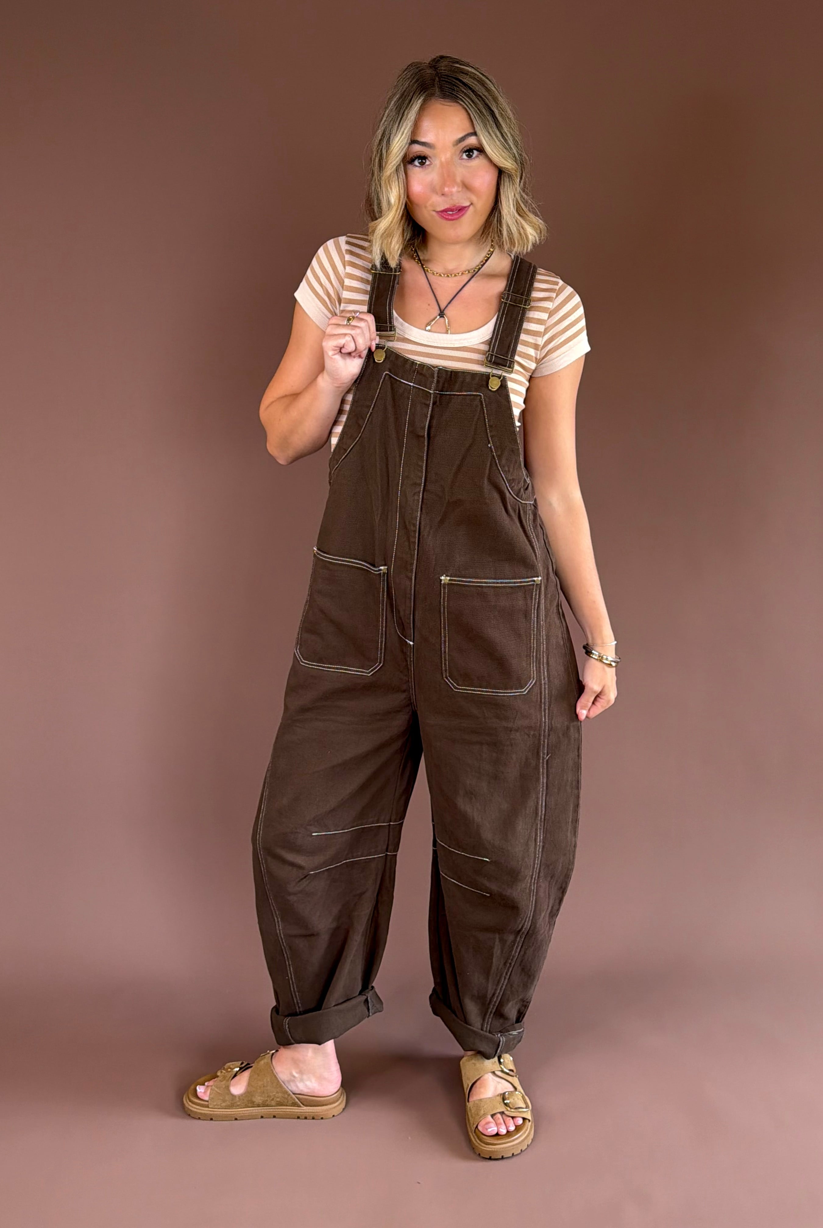 Women’s mocha brown denim overalls with adjustable straps, a relaxed wide barrel leg, patch pockets, and a straight bib front.