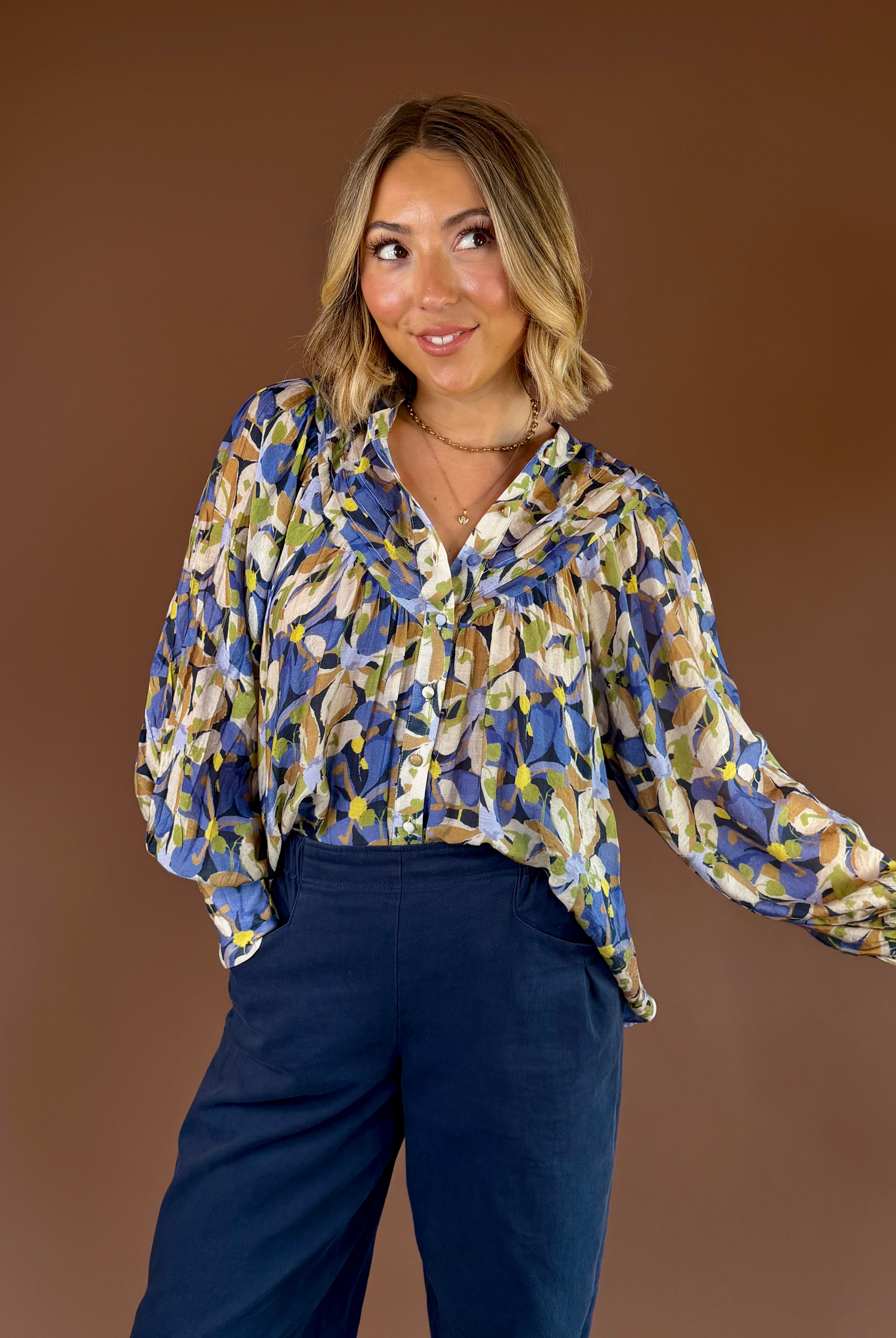 Blue and green botanical print button-down blouse with long sleeves, pleated details, and relaxed fit.