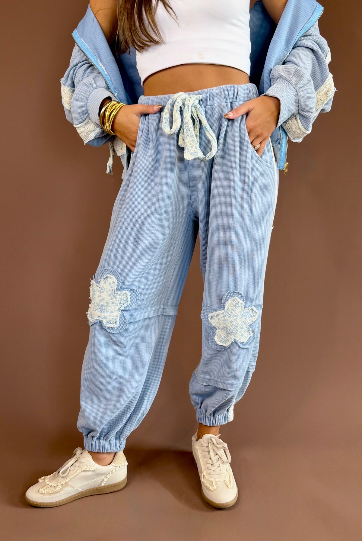 Vintage-wash thermal jogger pants with floral patchwork, contrast cotton trim, exposed seams, and drawstring waist.