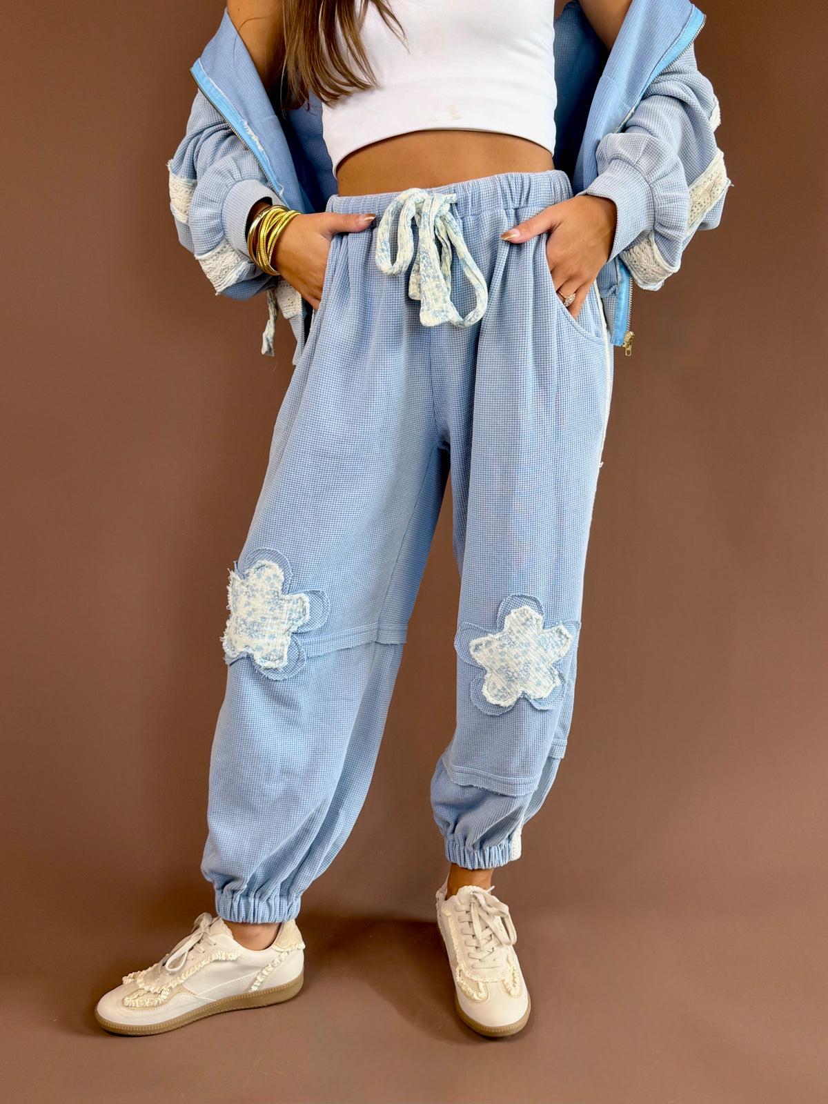 Vintage-wash thermal jogger pants with floral patchwork, contrast cotton trim, exposed seams, and drawstring waist.