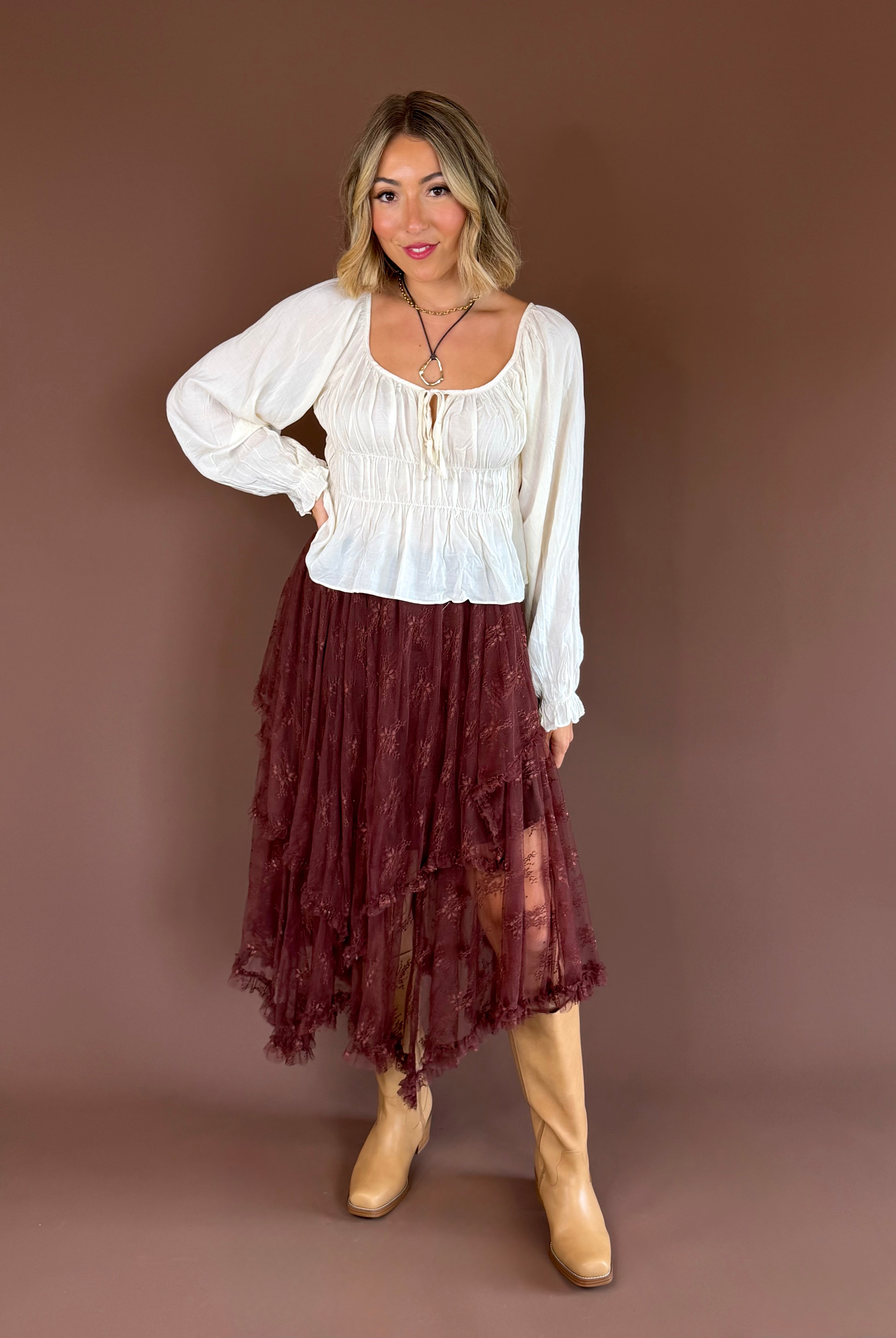 Primrose women’s ivory cotton blouse with a smocked bodice, scoop neckline, cap sleeves, and a feminine front bow detail.