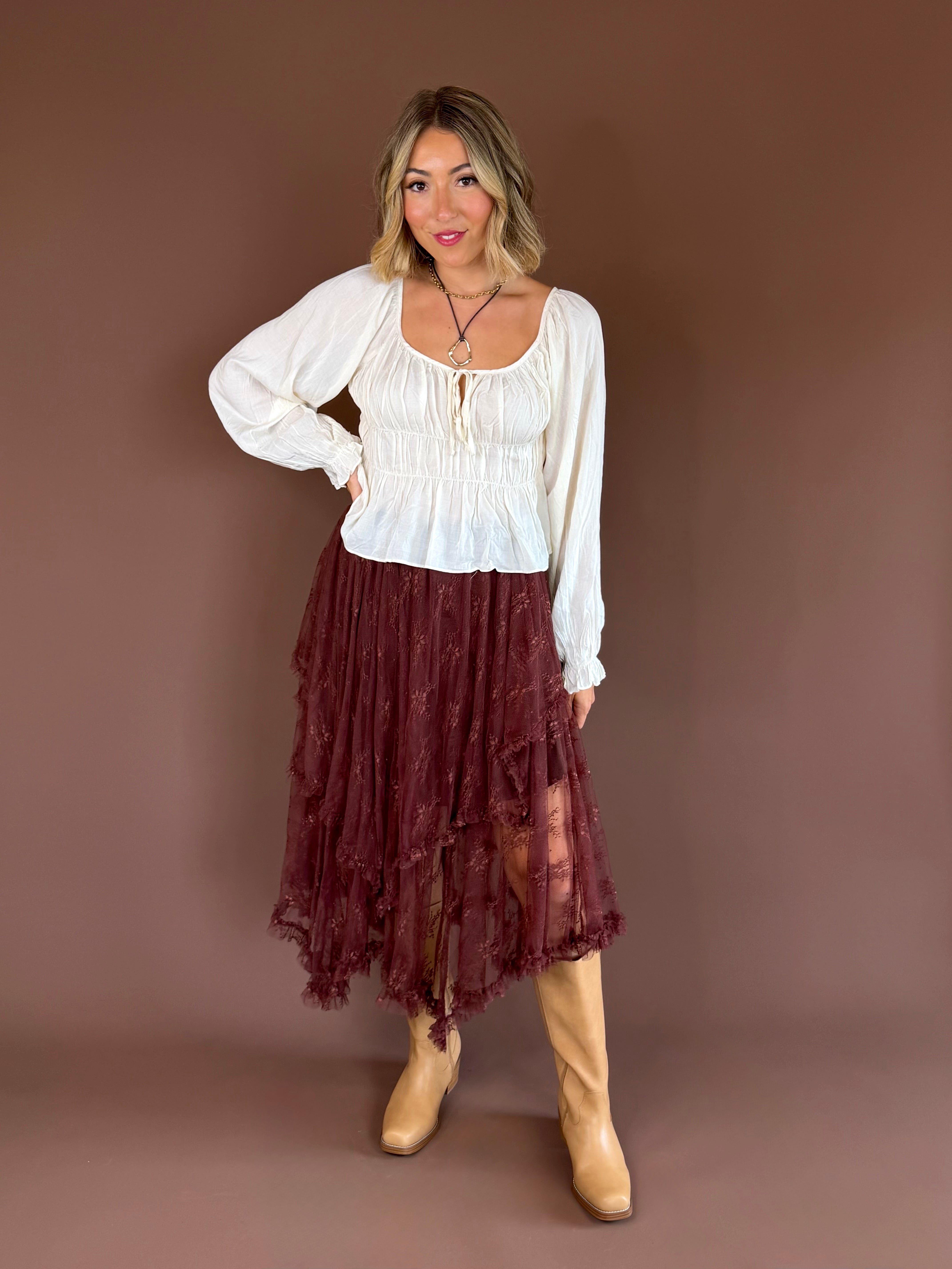 Primrose women’s ivory cotton blouse with a smocked bodice, scoop neckline, cap sleeves, and a feminine front bow detail.