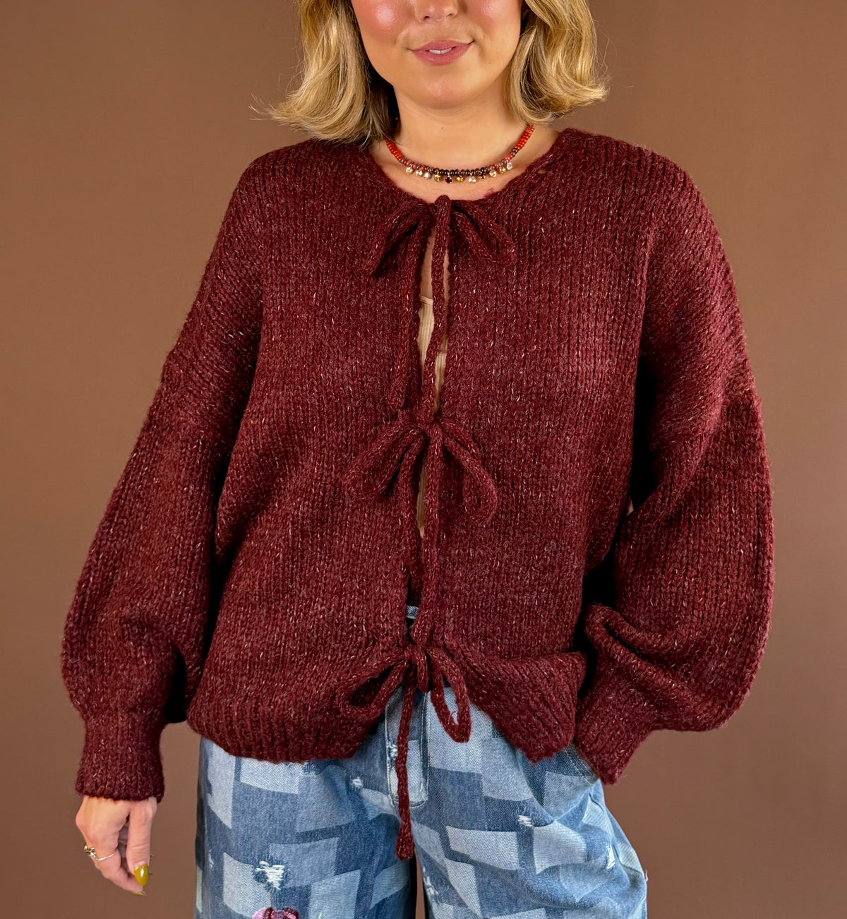 Take a Bow women's burgundy knit cardigan with bow tie front closures, long sleeves, and a relaxed silhouette.