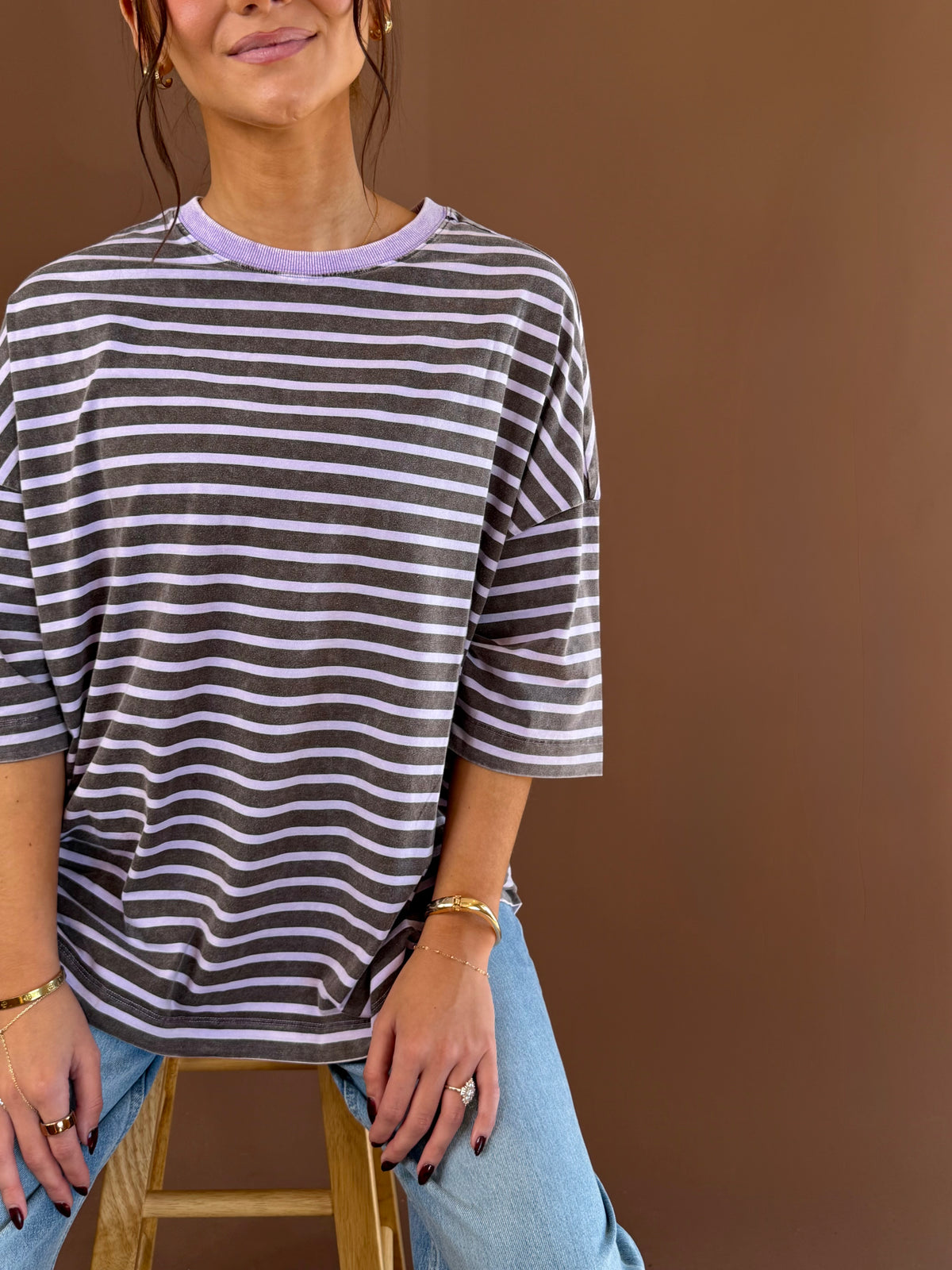 Model wearing a purple and white striped cotton tee with short sleeves and a round neckline, styled with jeans.