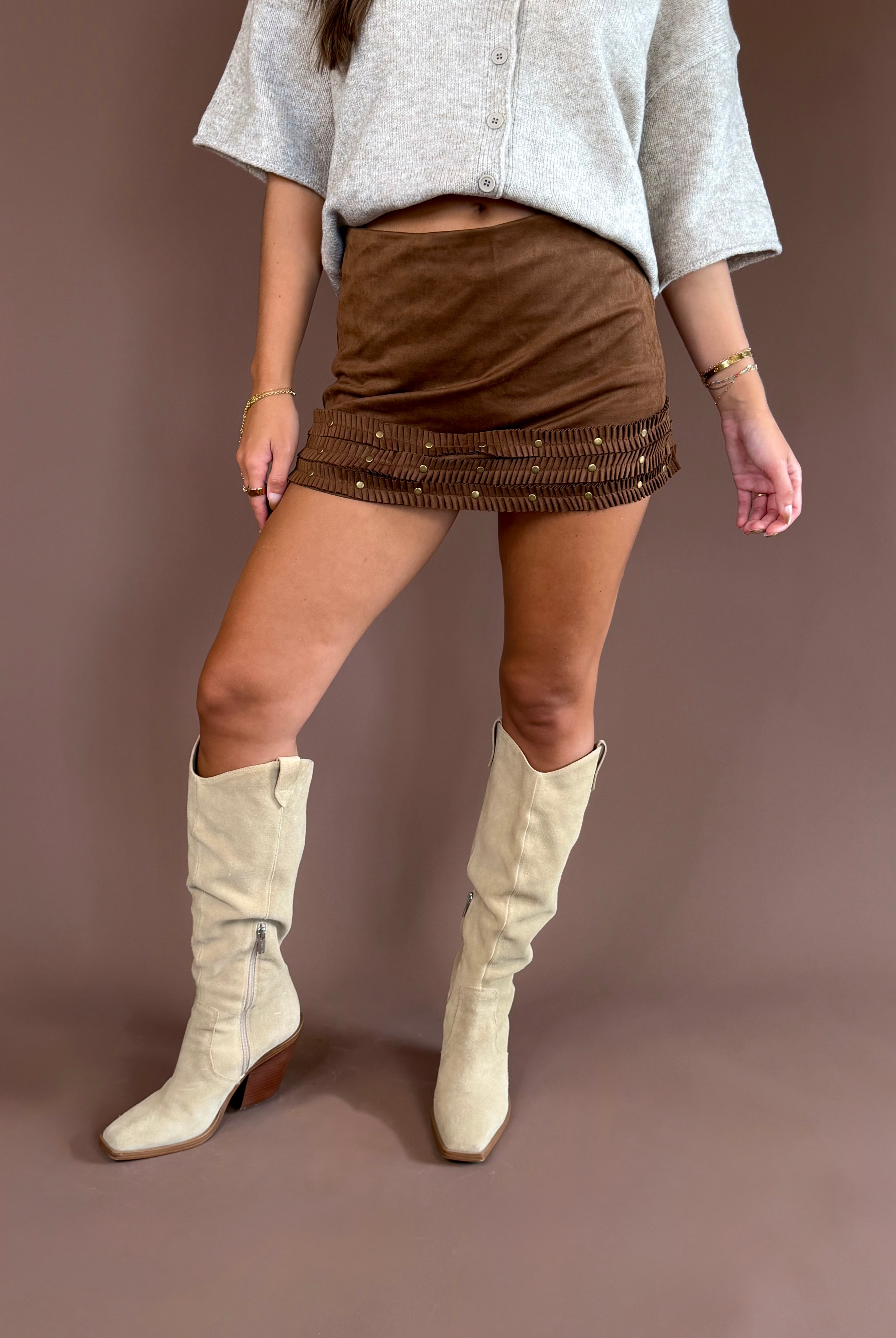 Wild West Darling women’s brown suede mini skirt with three ruffle tiers, studded western details, and built-in shorts.