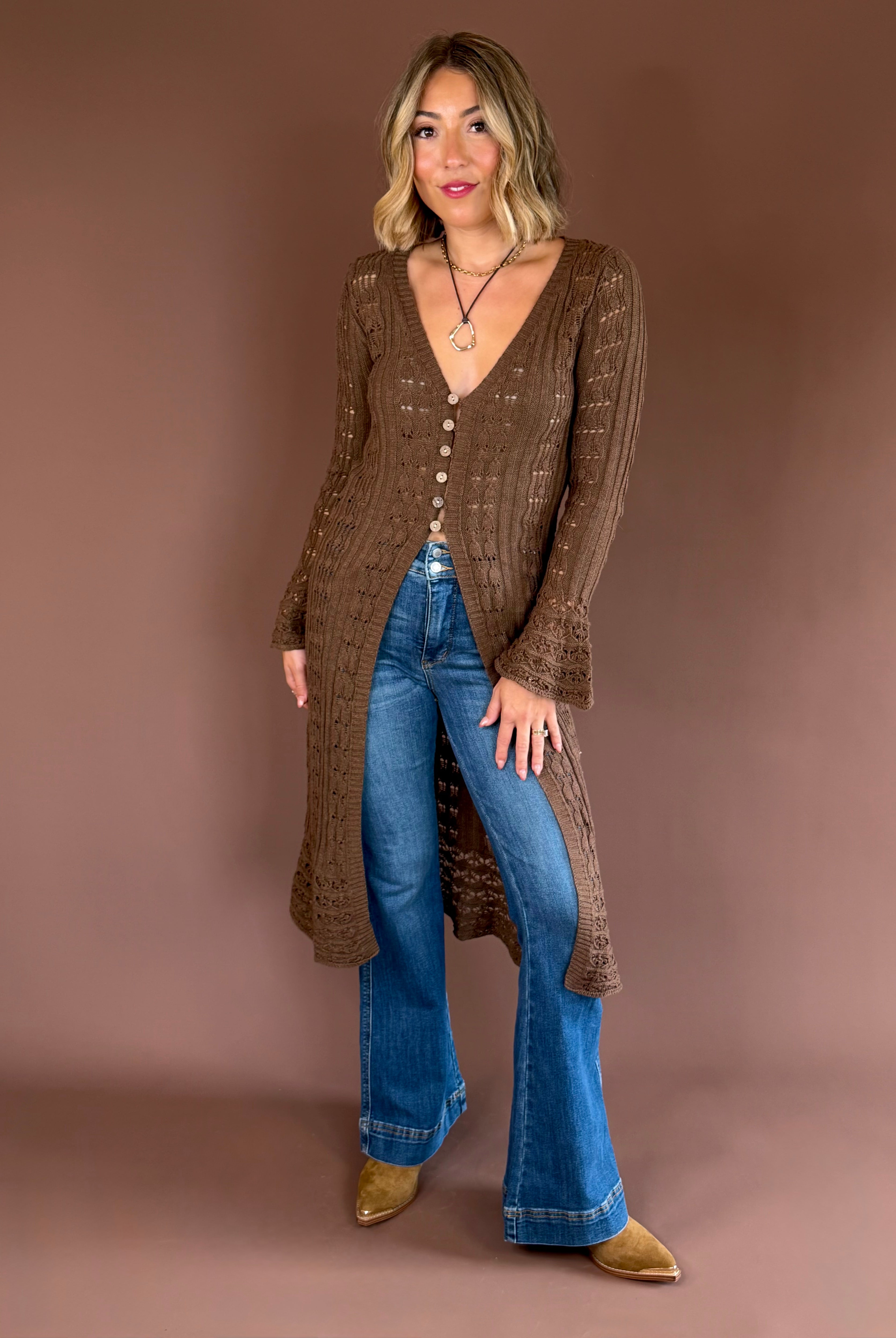 Women’s lightweight crochet-knit longline cardigan duster with a button front, flared sleeves, side slits, and midi length.