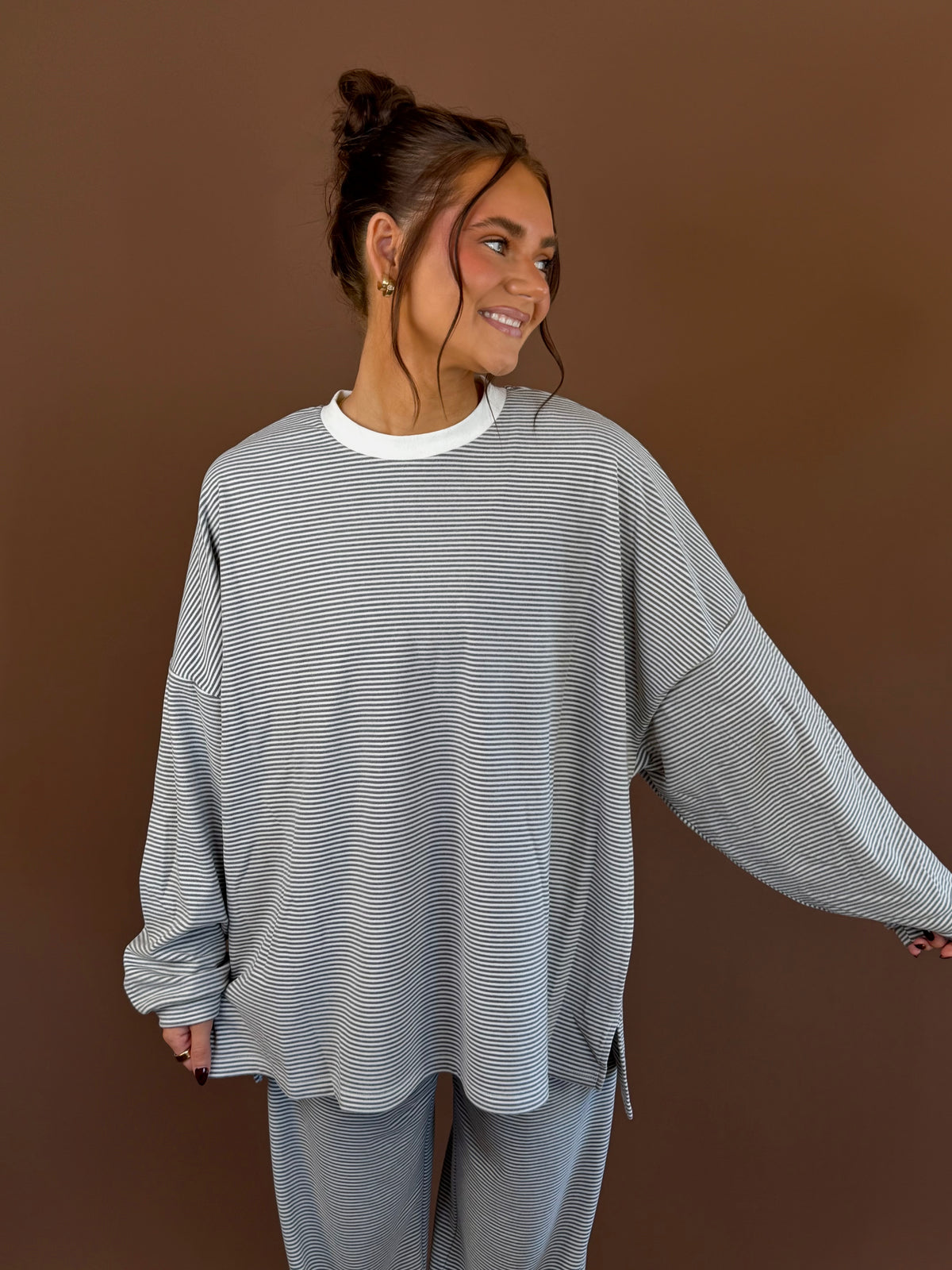 Model wearing an oversized gray striped long sleeve lounge top with white neckline trim and matching pants.