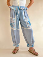 Light blue patchwork pants with decorative ruffles on a beige background, bandana print patchwork, shades of blue, white trim detail, ruffle waist sweatpant, synched bottom pant 