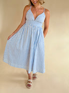 Woman wearing a blue and white striped dress on a beige background, blue and white stripe maxi, summer dress, elevated style, elegant dress, blue and white, pinstripe