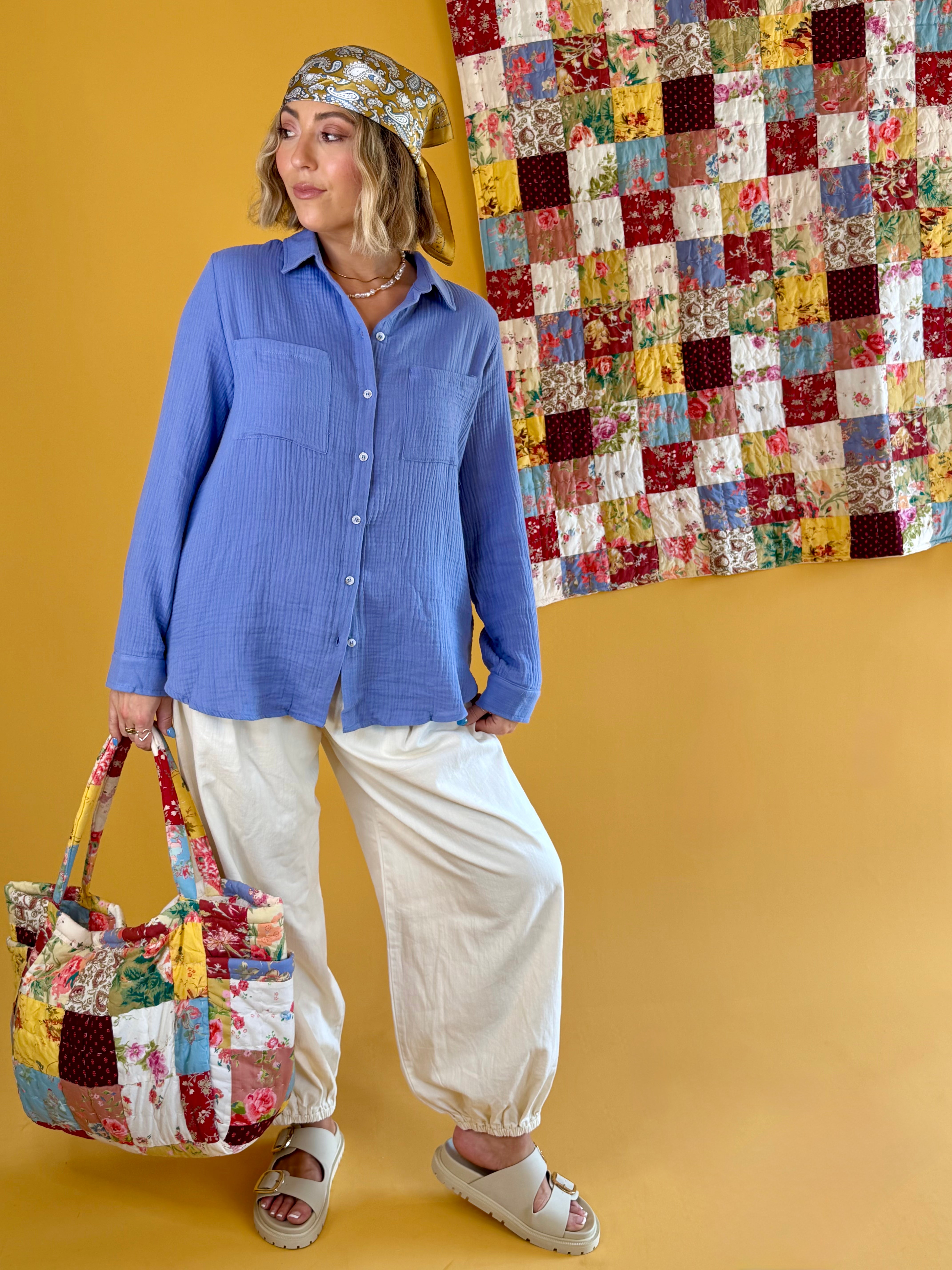 Woman holding a patchwork handbag with a colorful quilt in the background