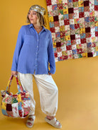 Woman holding a patchwork handbag with a colorful quilt in the background