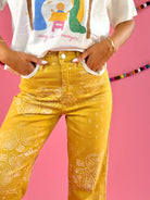 Waistband and front pocket detail: POPPY & PINE mustard yellow bandana paisley denim pants with frayed hems.