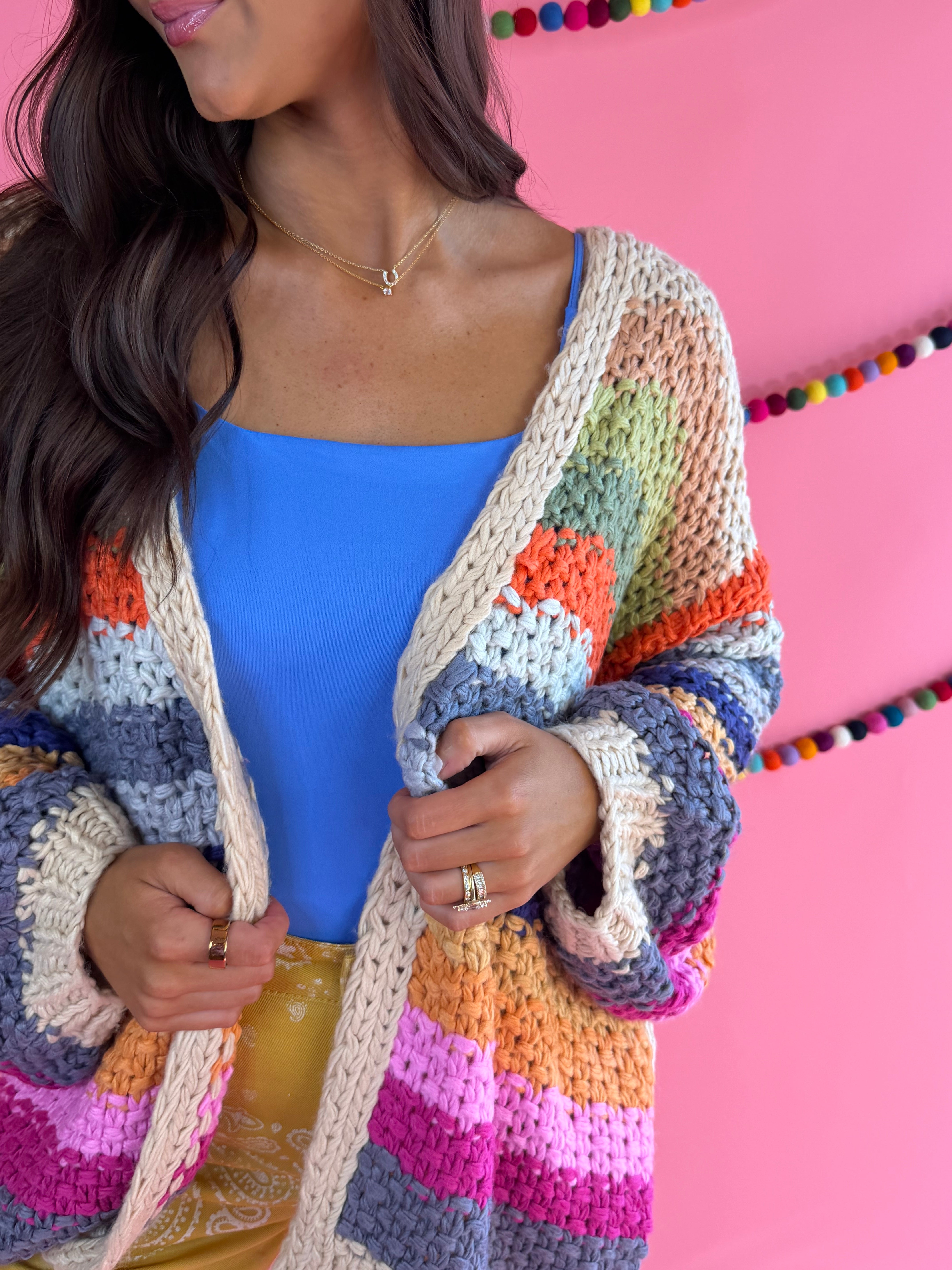 Knit and stripe detail: Cream Rainbow Cardigan with multicolor stripes, an open front, and hip pockets.