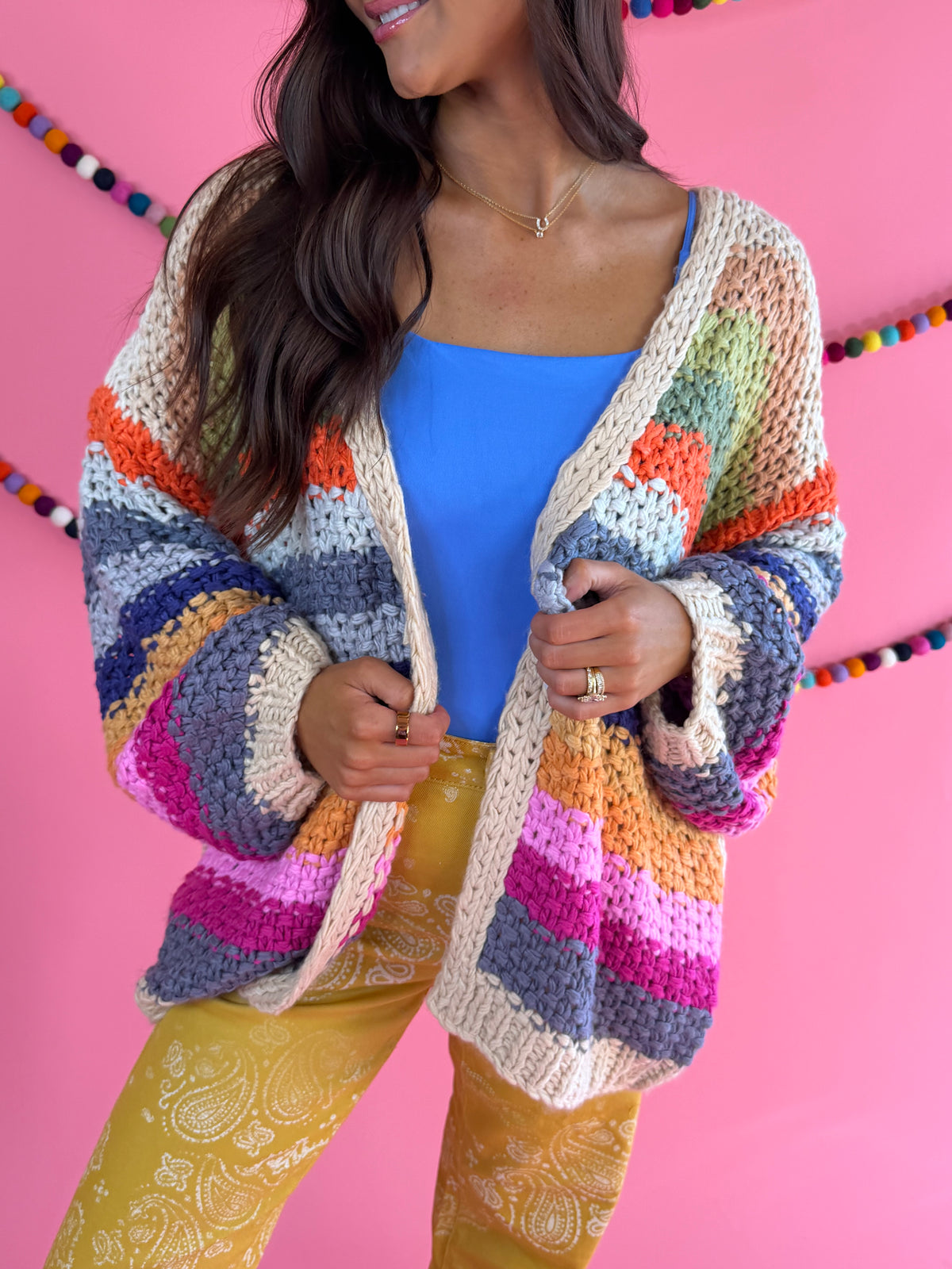 Front fit view: Cream Rainbow Cardigan with multicolor stripes, an open front, and hip pockets.