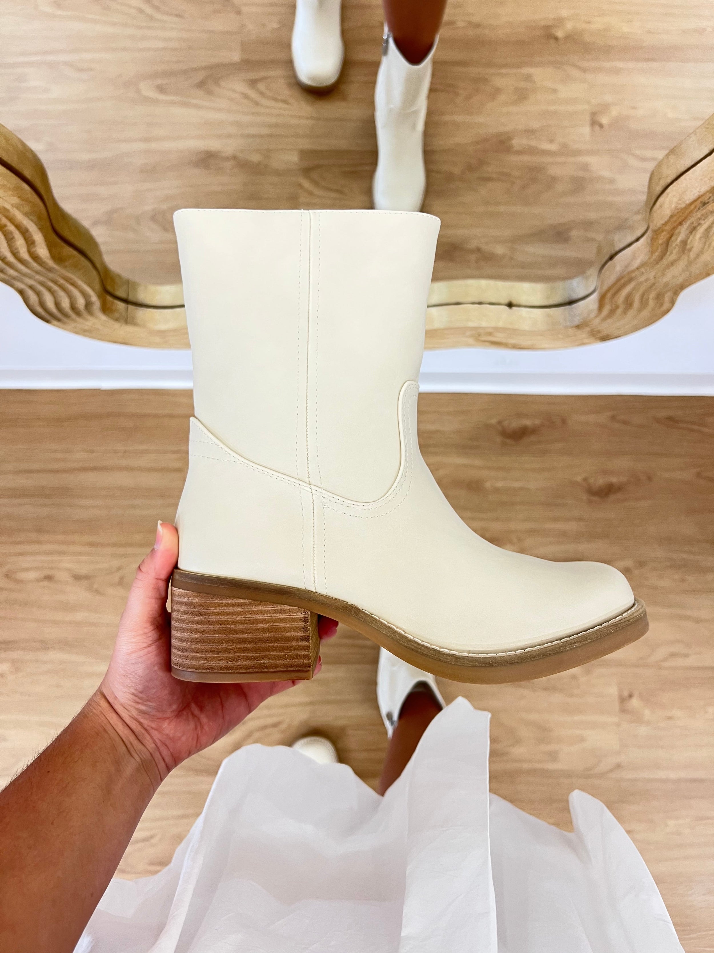 White boot held in a hand with a wooden floor background, TRENDY BOOT, it girl boot, bootie, boho style, coastal, bone