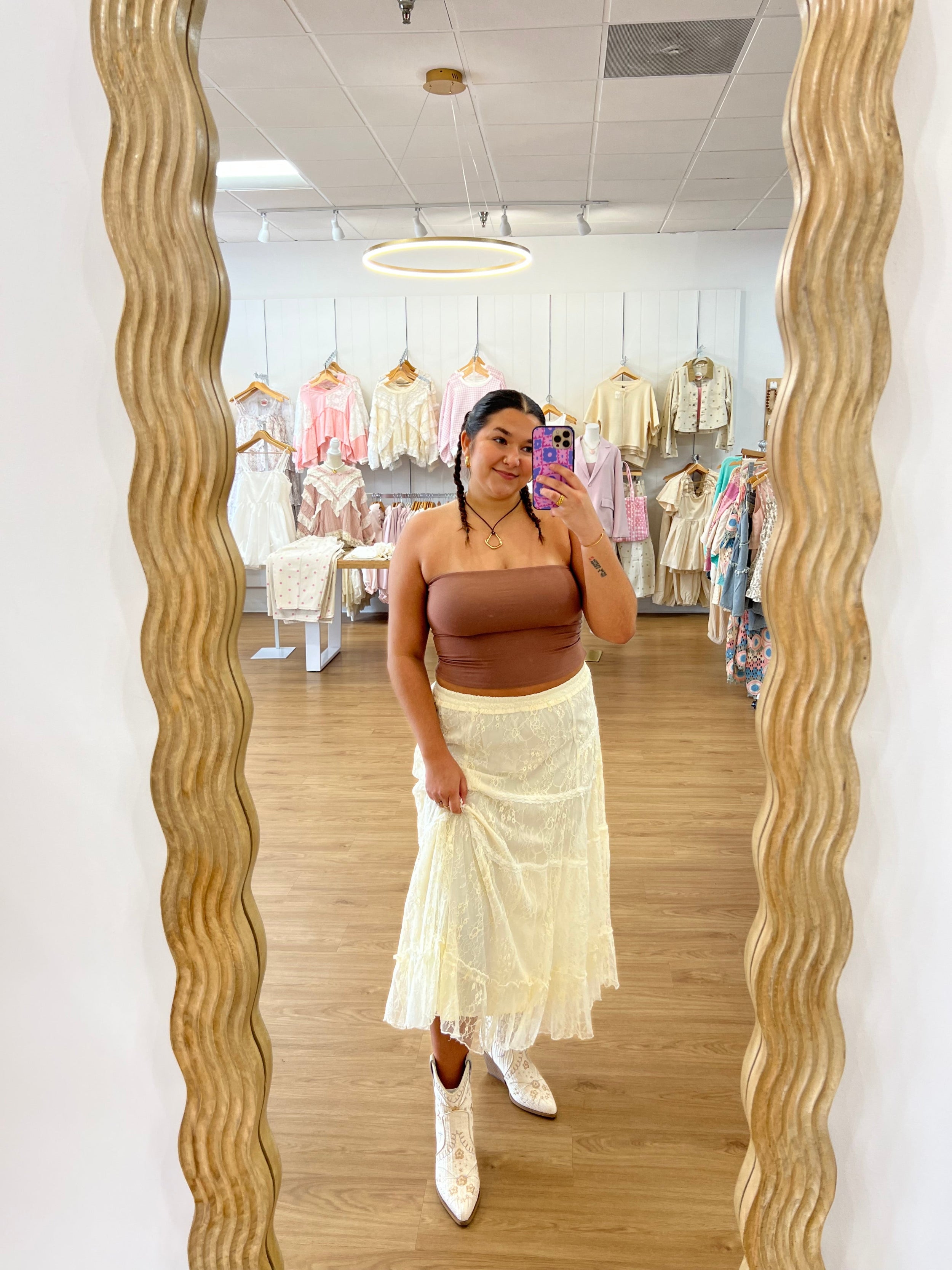 White embroidered boot held by a hand on a wooden floor with lace fabric. coastal cowgirl, raffia, western beach boot, boho western outfit with boots