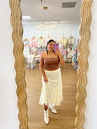 White embroidered boot held by a hand on a wooden floor with lace fabric. coastal cowgirl, raffia, western beach boot, boho western outfit with boots