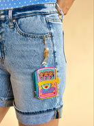 Colorful backpack charm on a denim shorts pocket against a beige background, sardine charm, mini wallet, keychain wallet, beaded detail, accessory, gifts 