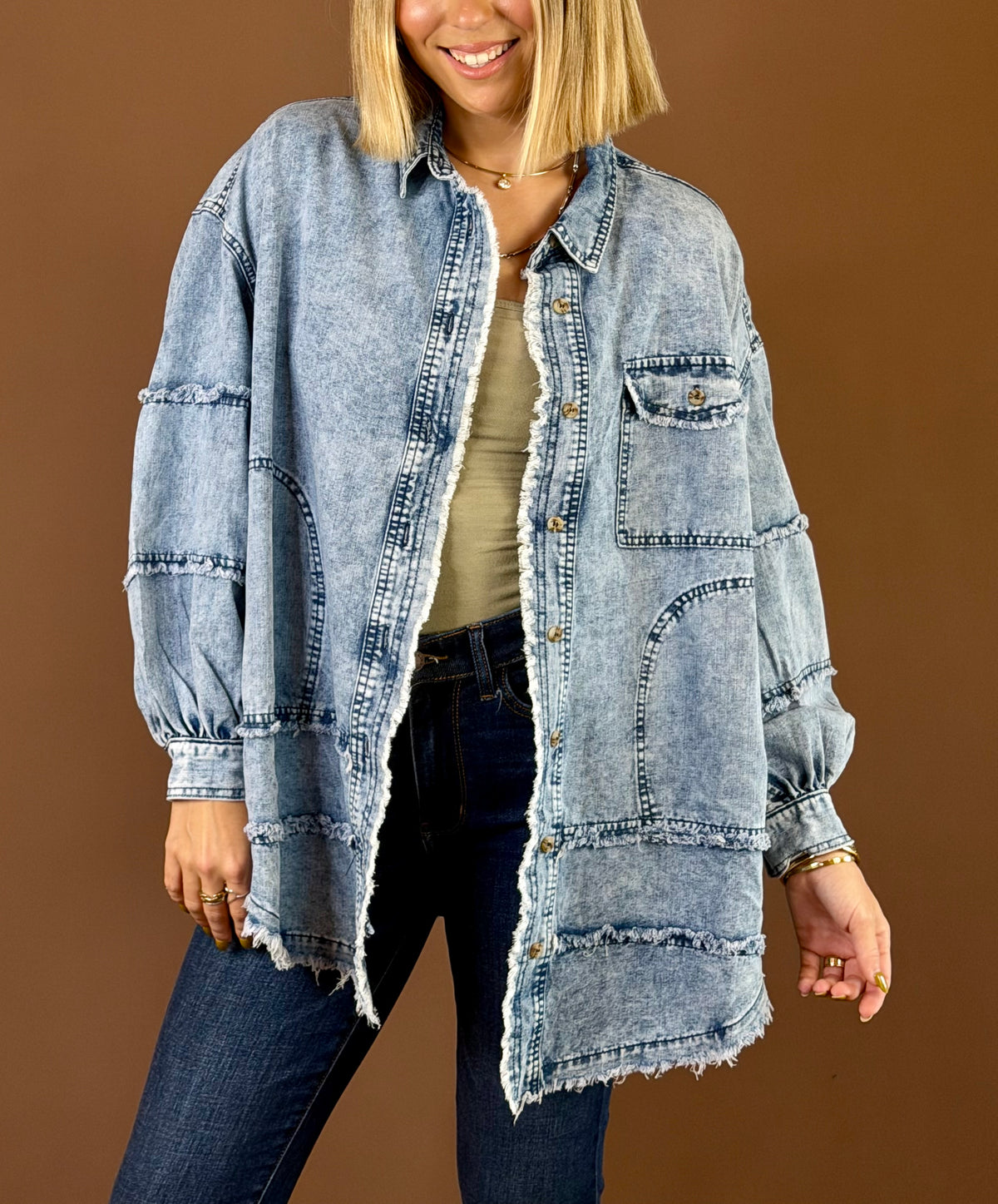 Model wearing the Blue Jean Baby washed blue oversized denim shacket with exposed seams, chest pocket, and frayed edges over a yellow top and jeans.