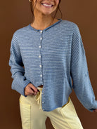 Model wearing a dusty blue pinstripe button-front cardigan with long sleeves, styled with pale yellow pants.