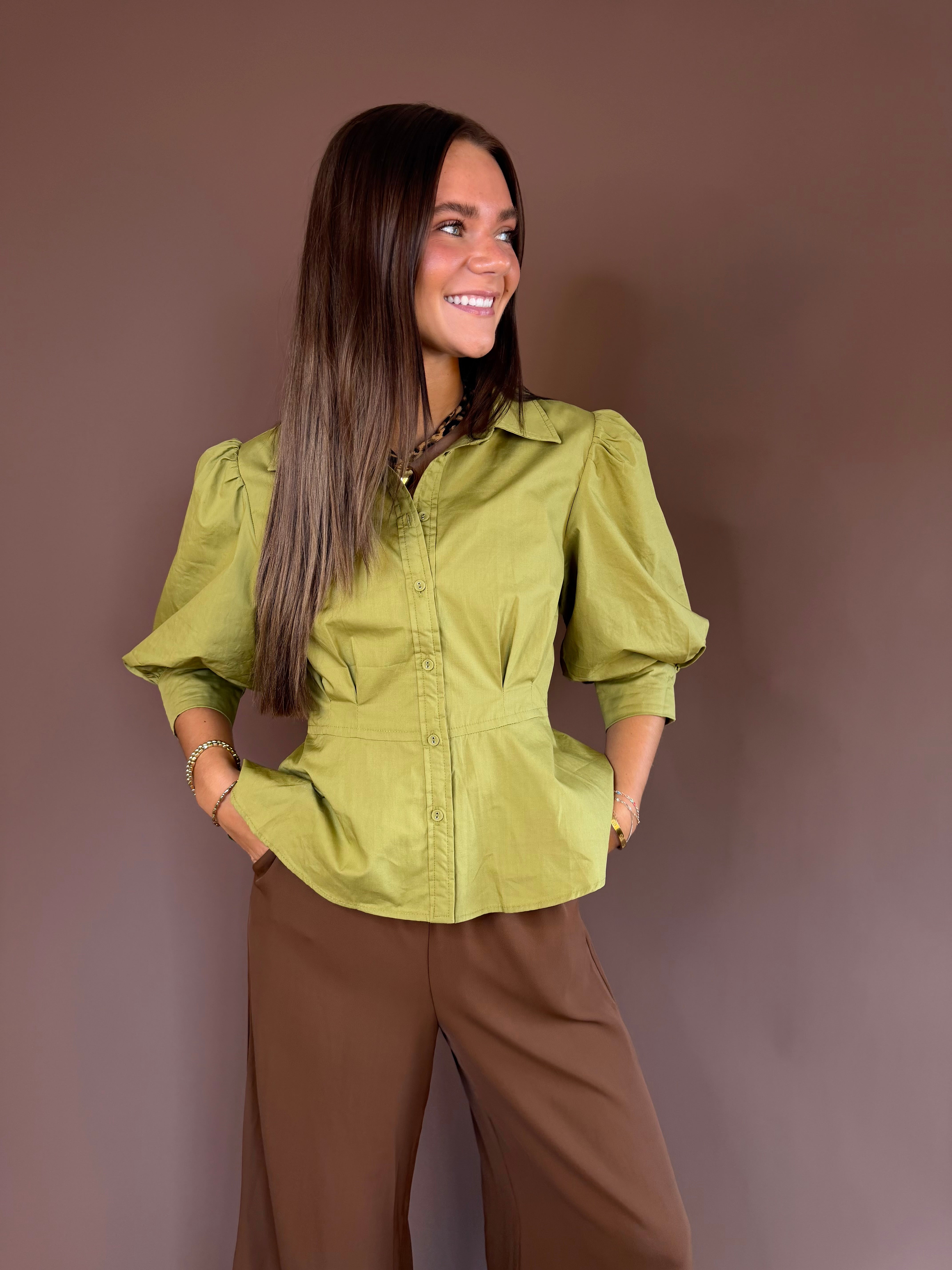 Olive green cotton button-down blouse with three-quarter puff sleeves and a flared peplum hem.