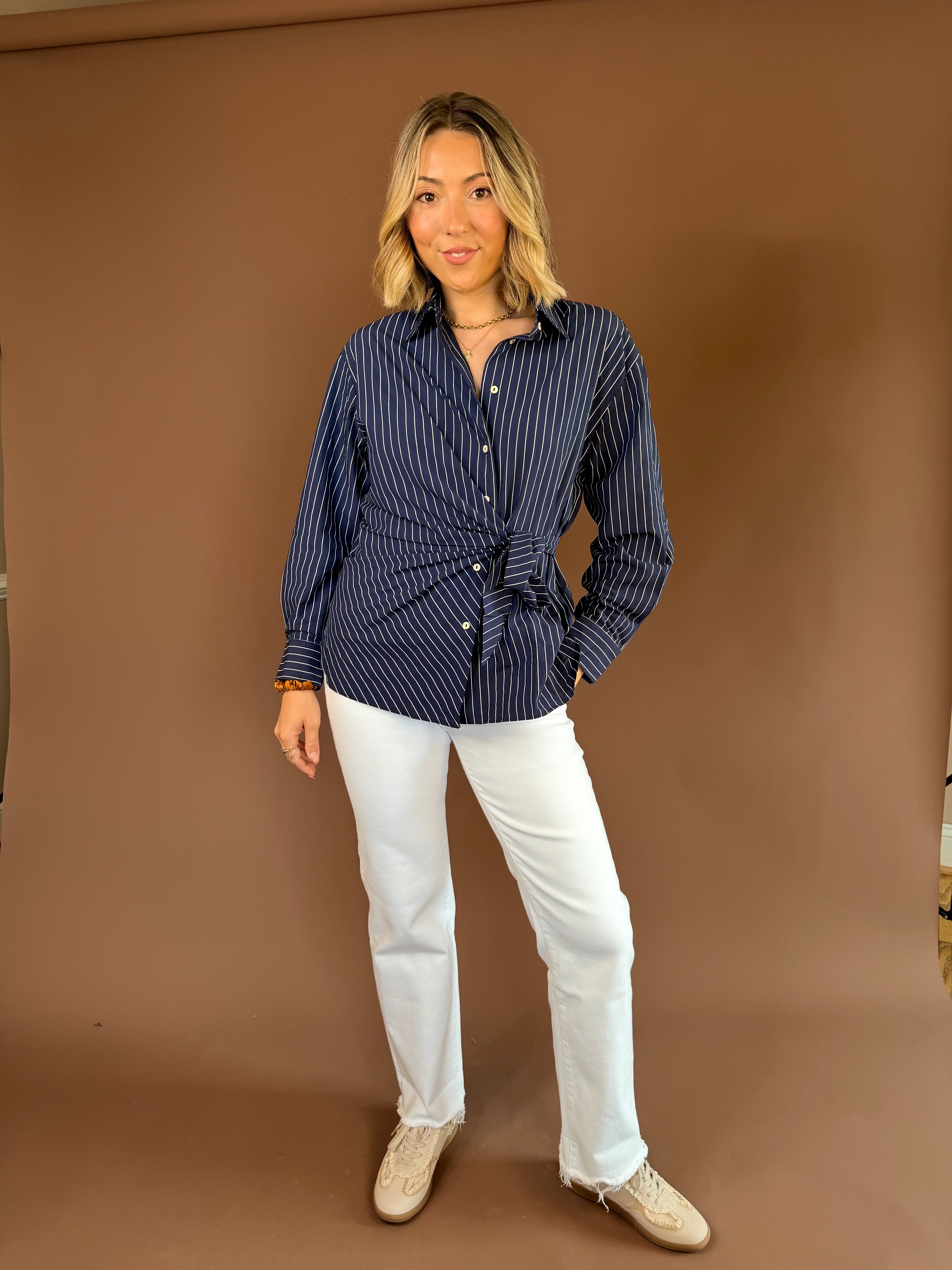 Navy blue pinstripe button-down blouse with long sleeves and an adjustable side-tie waist.