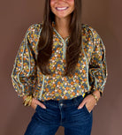 Brown cotton blouse with an allover floral print, V-neckline, three-quarter sleeves, and relaxed fit.