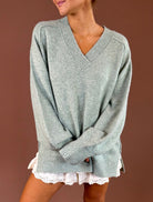 Model wearing the Forever Favorite mint sage oversized V-neck sweater with dropped shoulders and ribbed cuffs over white lace-trim shorts.
