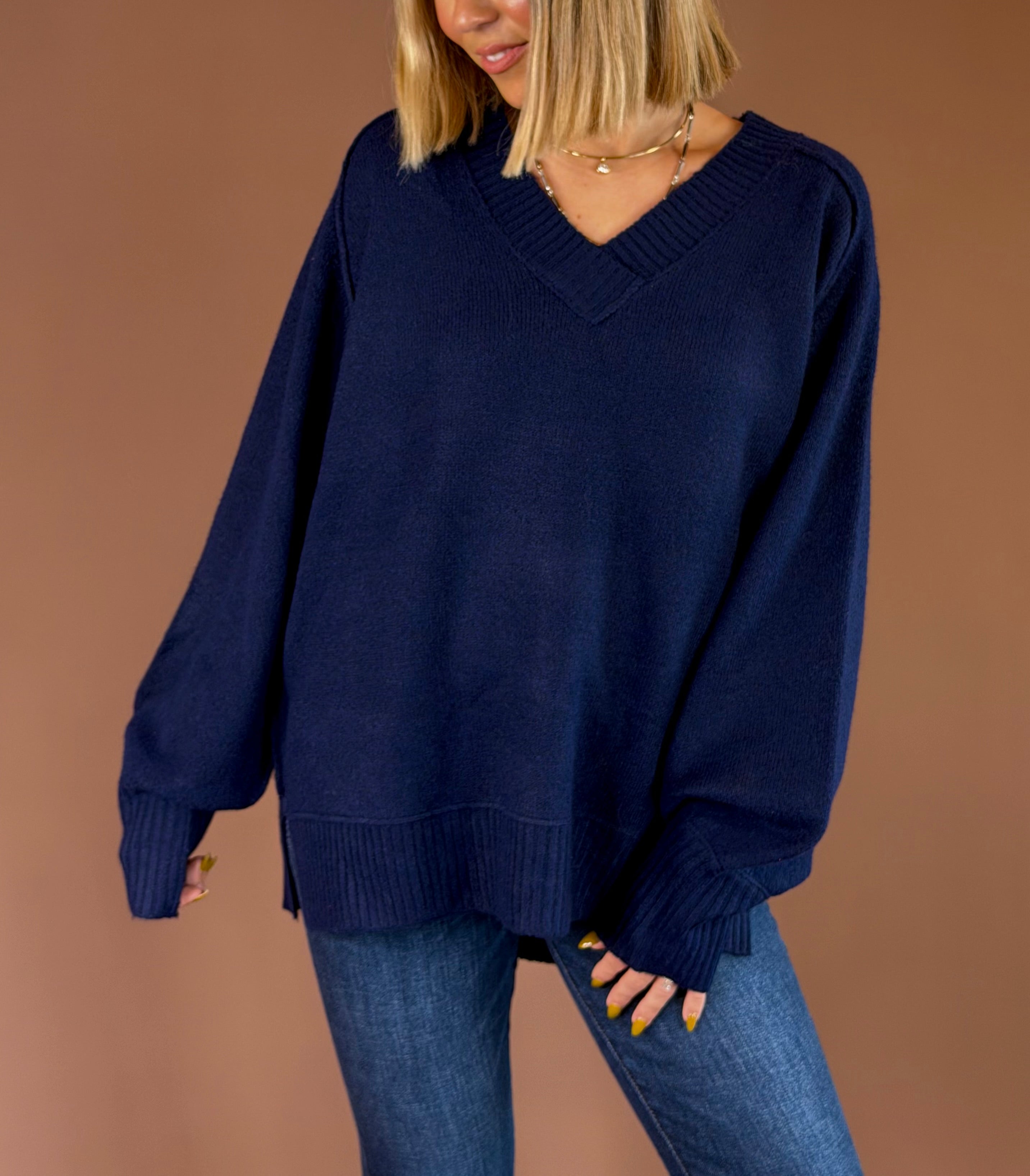 Model wearing the Forever Favorite navy oversized V-neck knit sweater with long sleeves and ribbed trim, paired with blue jeans.