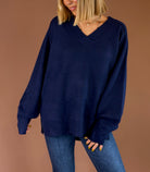 Model wearing the Forever Favorite navy oversized V-neck knit sweater with long sleeves and ribbed trim, paired with blue jeans.
