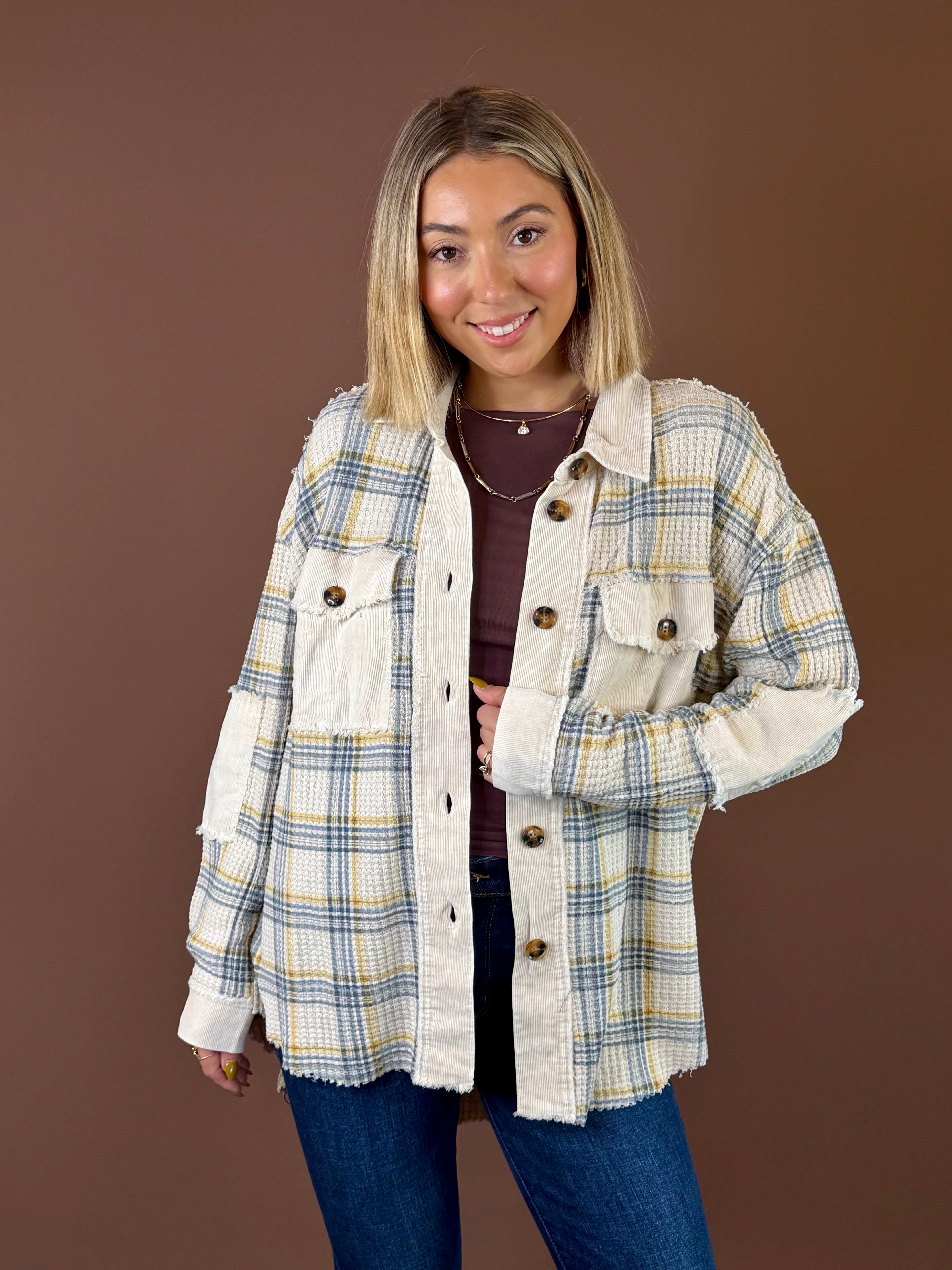 Model wearing the Golden Fields cream, yellow, and blue plaid shacket with contrasting textured panels, front pockets, and dark buttons over jeans.
