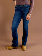 Front view of a model wearing Judy Blue dark wash mid-rise bootcut jeans with a 32-inch inseam, styled with a brown top and pointed-toe boots.