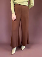 Chocolate brown high-waisted trouser pants with a wide leg, clasp-front closure, and side pockets.