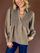Taupe brown textured babydoll blouse with a collared V-neckline, long cuffed sleeves, and flowy fit.
