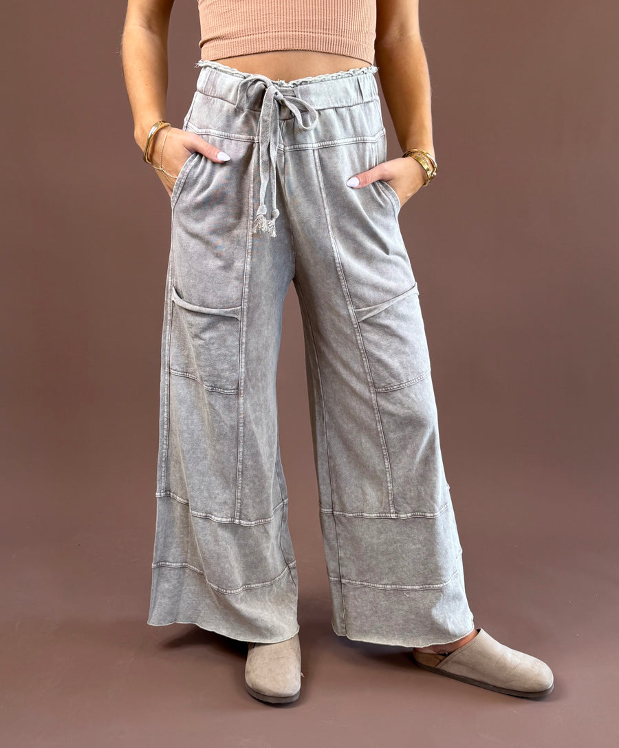 Mushroom Mist women’s mineral-wash pants with a relaxed wide-leg shape, elastic drawstring waist, roomy pockets, and raw-edge hems