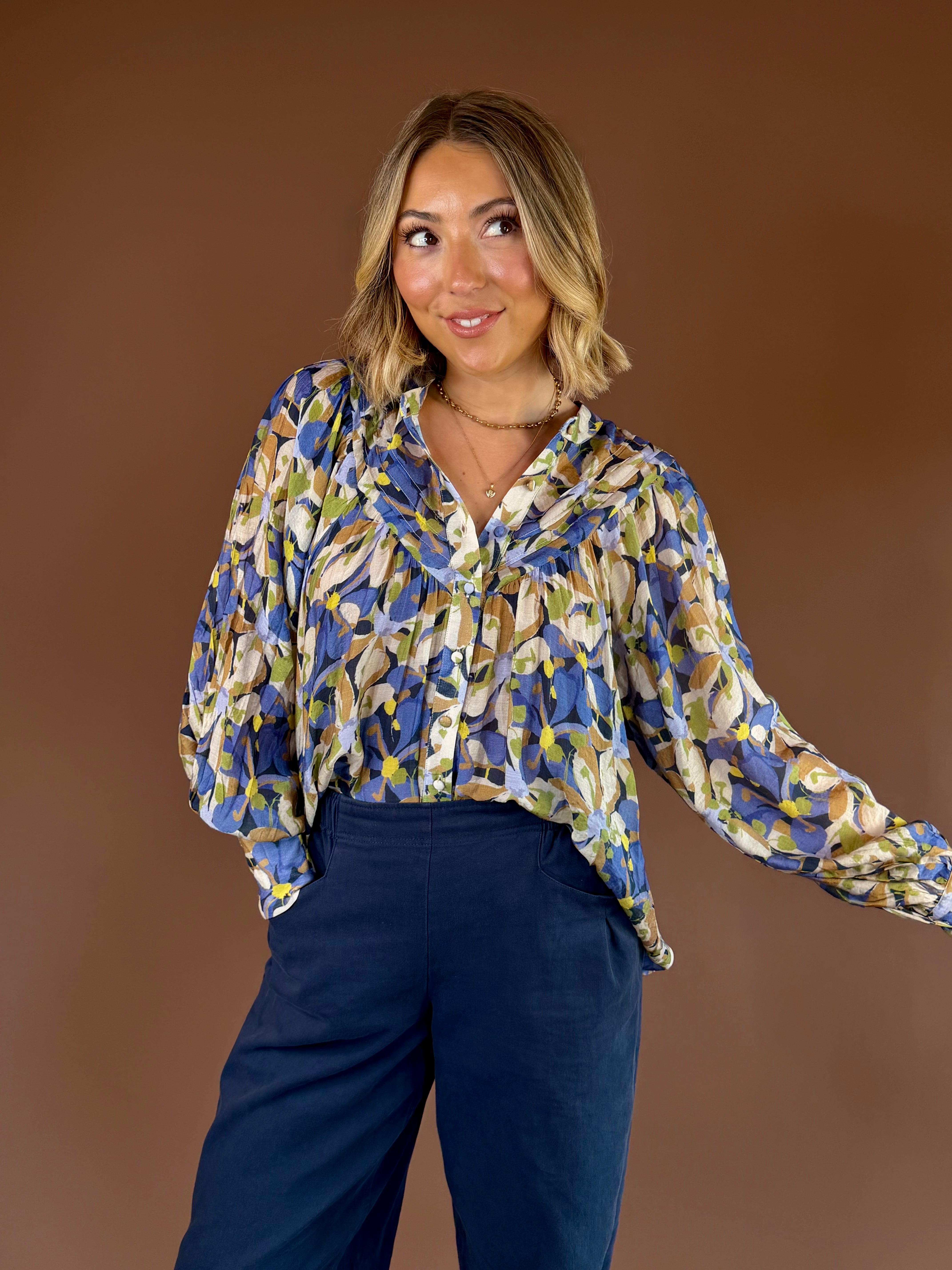 Blue and green botanical print button-down blouse with long sleeves, pleated details, and relaxed fit.
