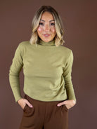 Olive green long-sleeve knit top with a rolled mock neckline and softly fitted layering silhouette.