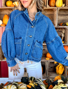 Model wearing a medium blue wash denim jacket with a funnel neckline, button-front closure, balloon sleeves, and front pockets.