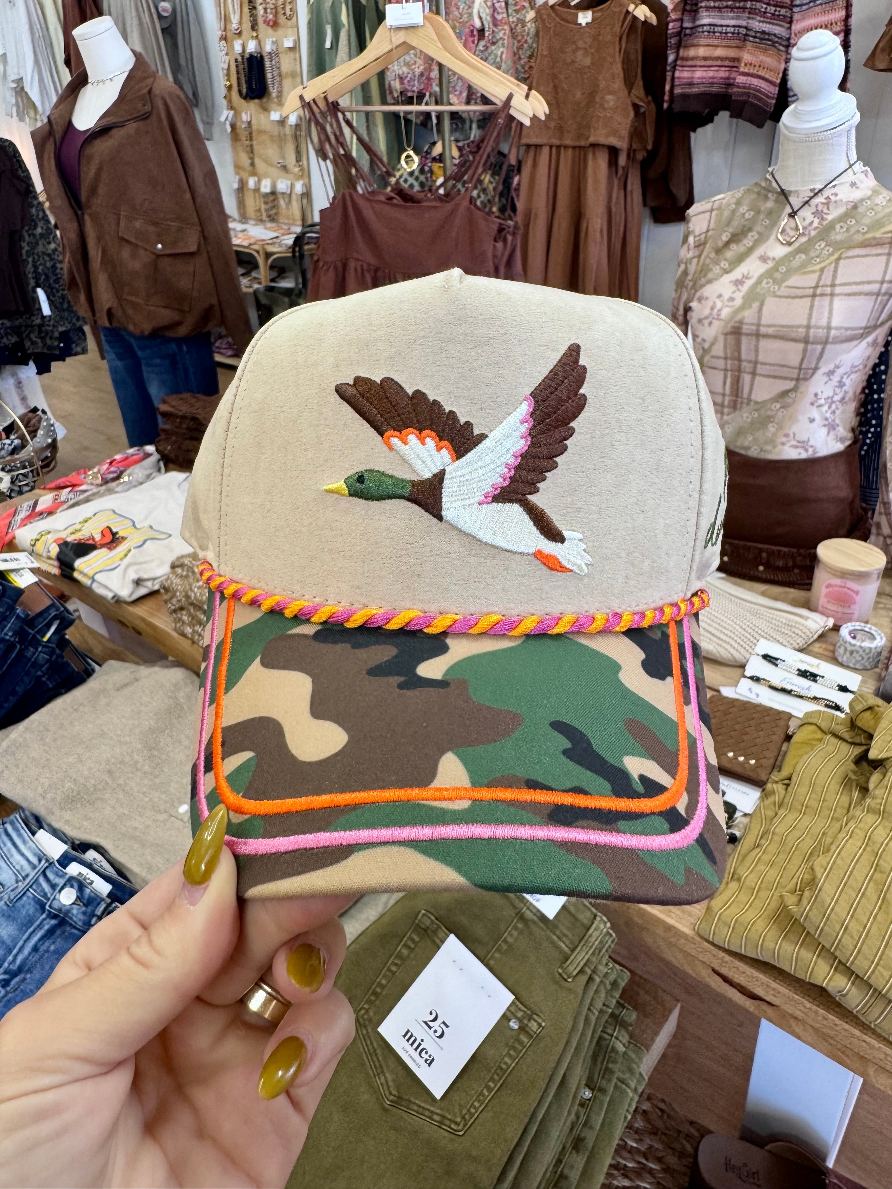 Cream and camouflage trucker-style hat with an embroidered flying mallard duck on the front panel and a colorful rope trim across the brim.