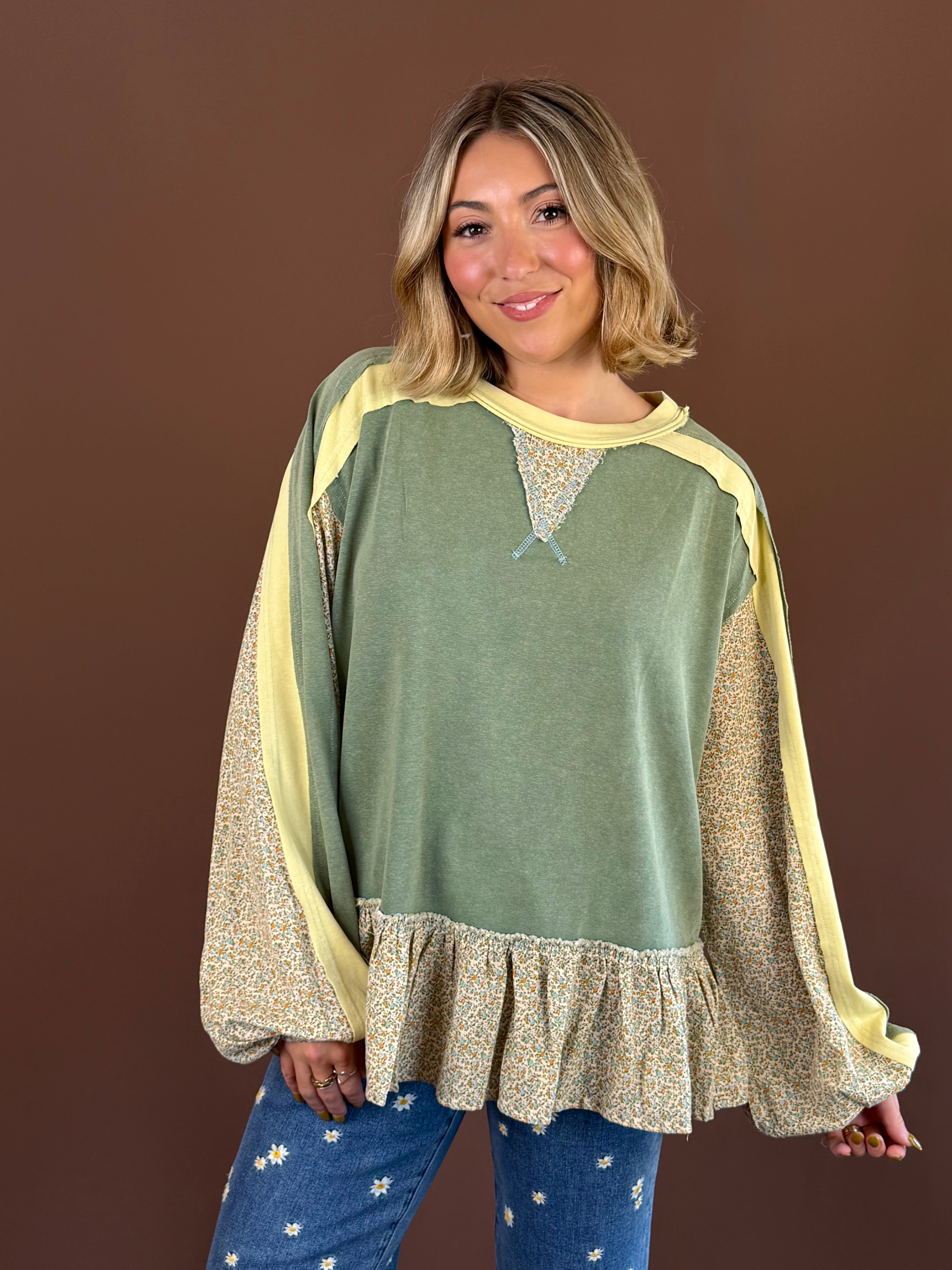 Pressed Petals women's floral-print top with long sleeves, a round neckline, exposed seam stitching, and a ruffled hem.