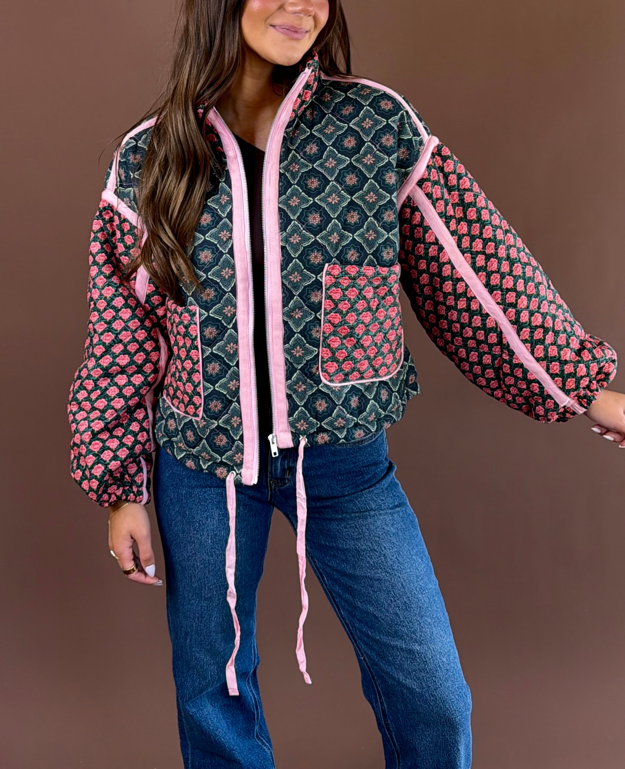 Rosy Daydream women’s quilted jacket in a rose multicolor floral print with a high neck, zip front, pockets, and adjustable cinch waist